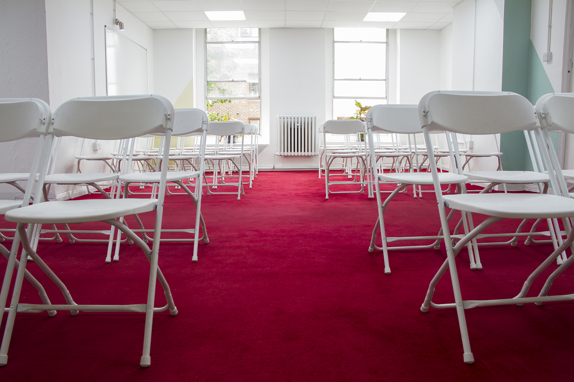 Events Space in Space4 with white chairs on red carpet, perfect for workshops and seminars.