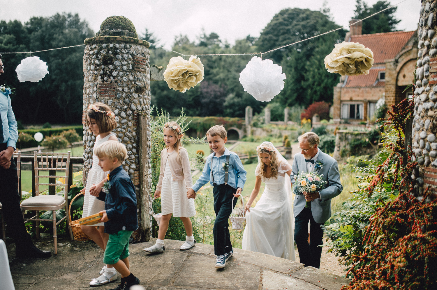 Outdoor wedding procession in Voewood Gardens with whimsical paper pom-poms.