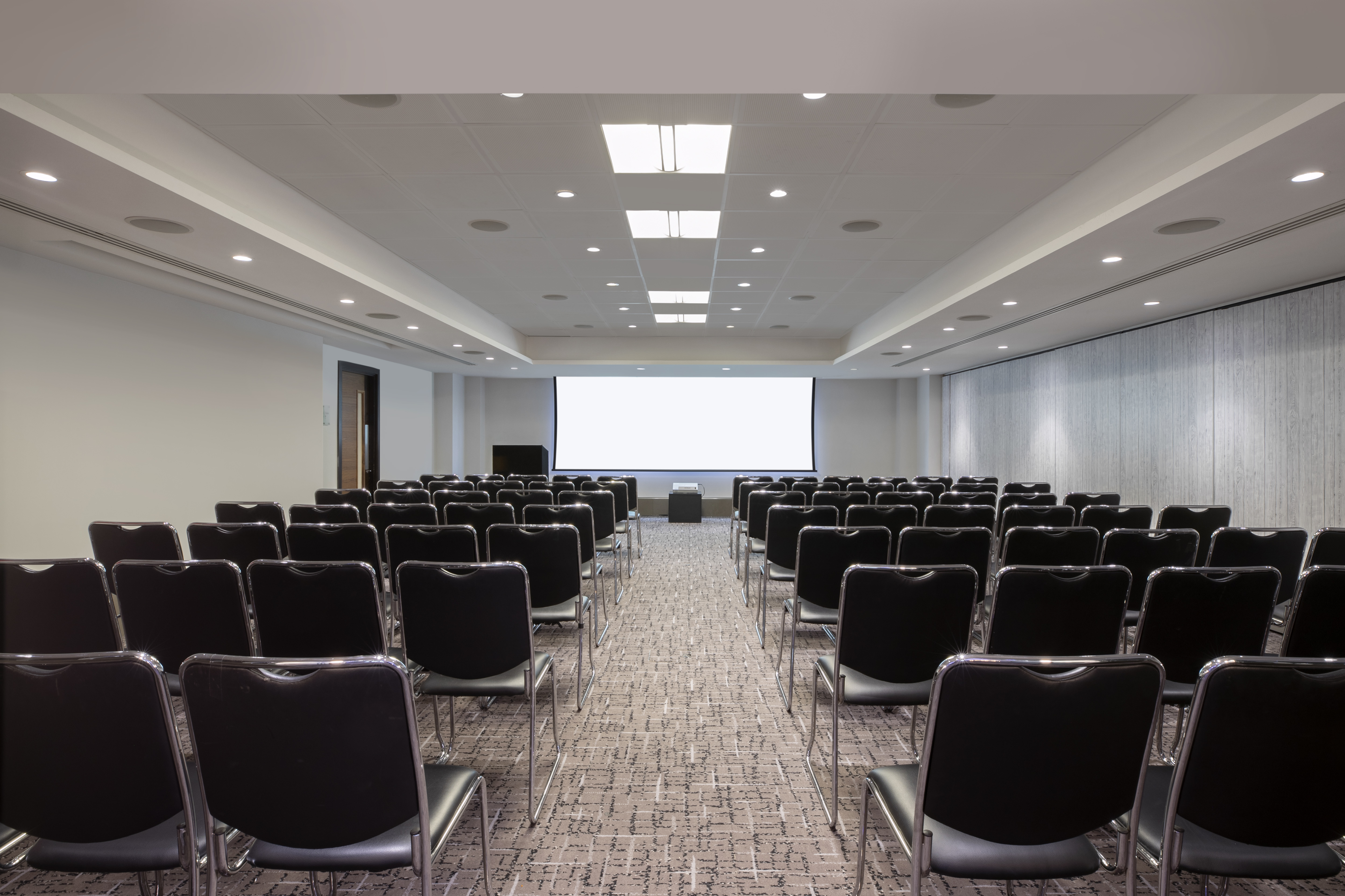 Versatile meeting space with black chairs at Leonardo Royal Hotel London Tower Bridge.