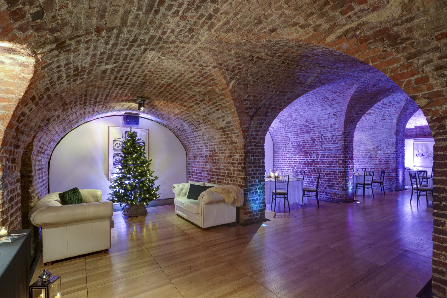 "Stylish RSA House Christmas party with exposed brick arches and festive tree."