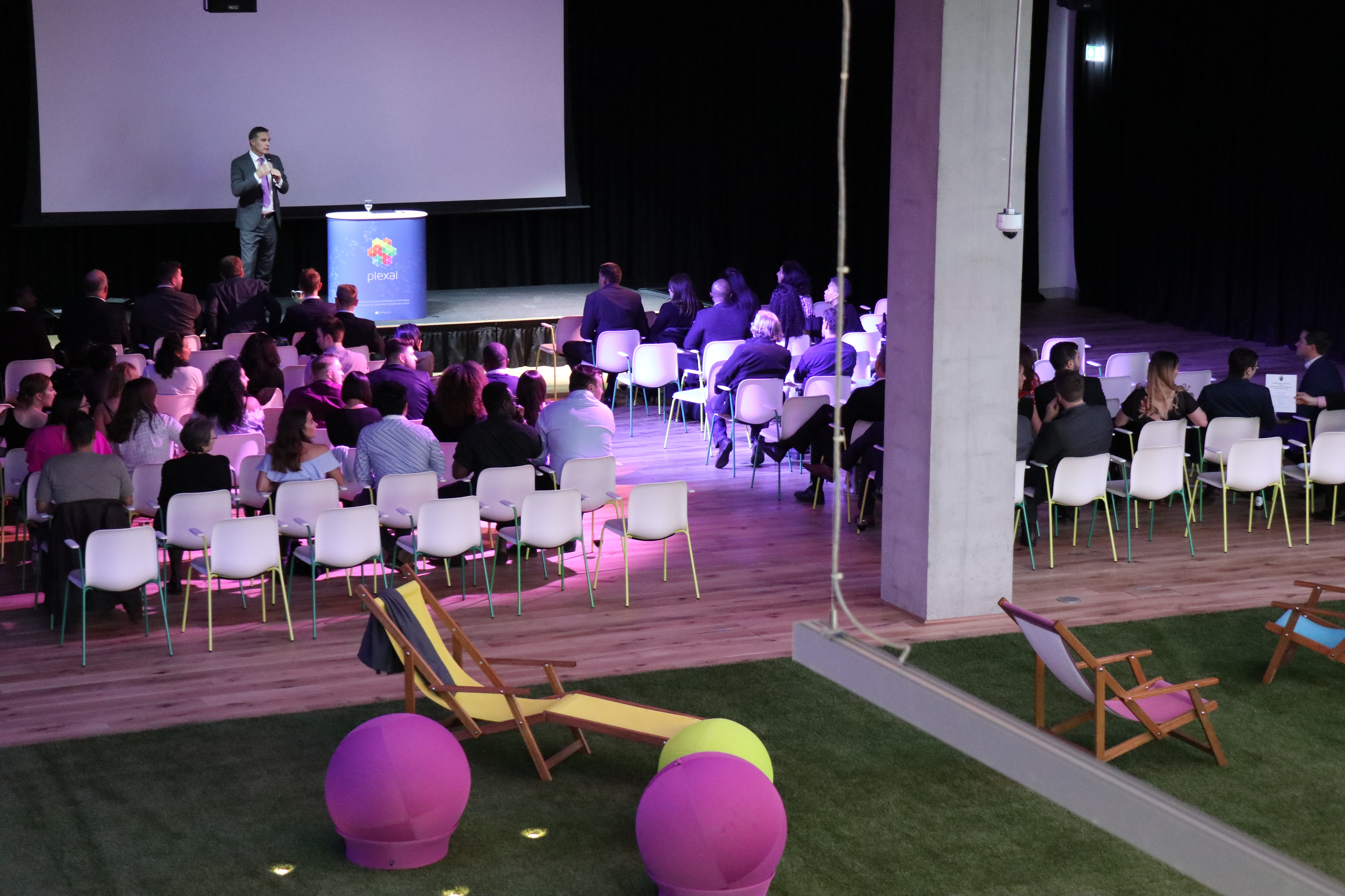 Dynamic event space with speaker, colorful seating for presentations and meetings.