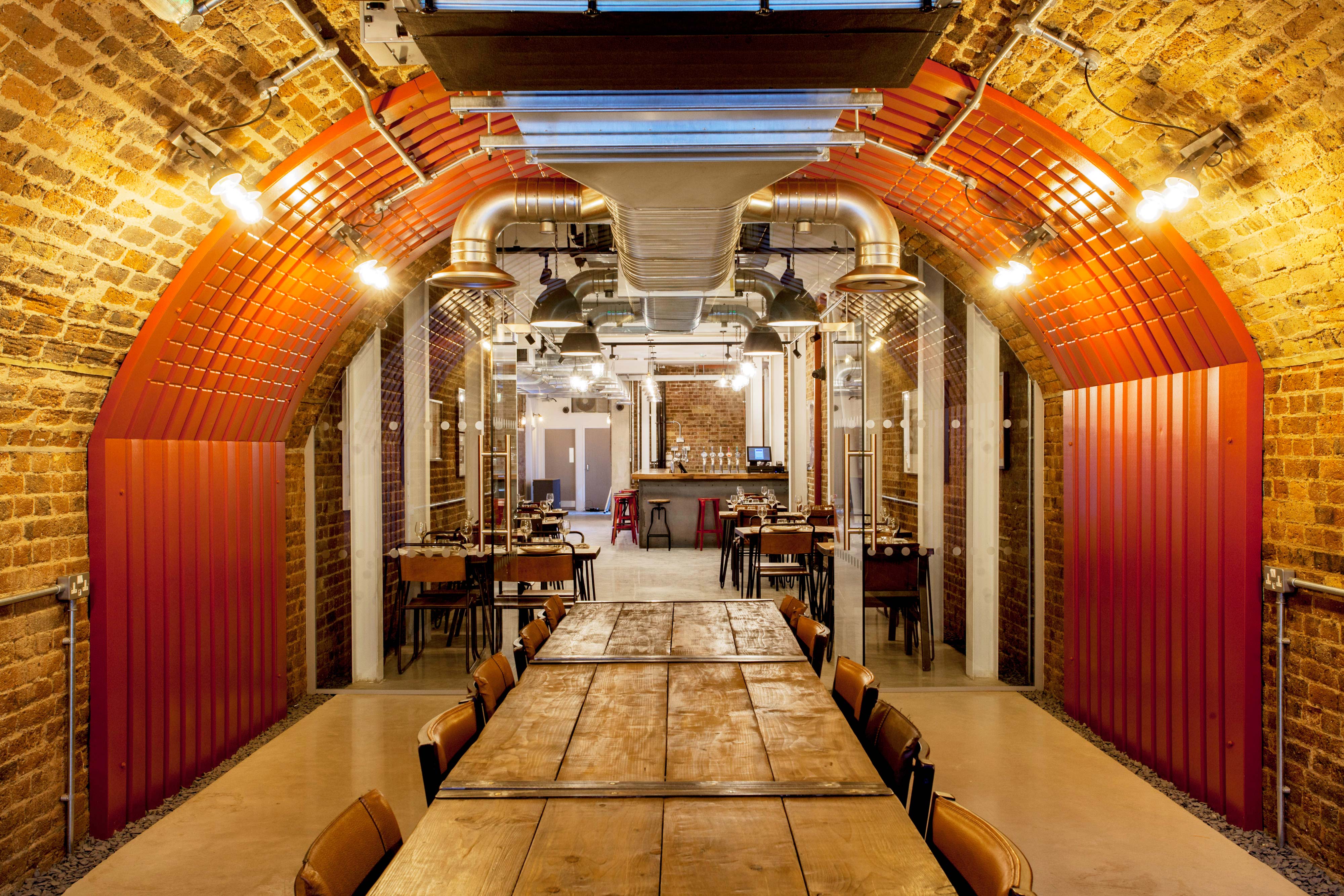 Stylish industrial-chic event space with arched ceiling for meetings and dinners.