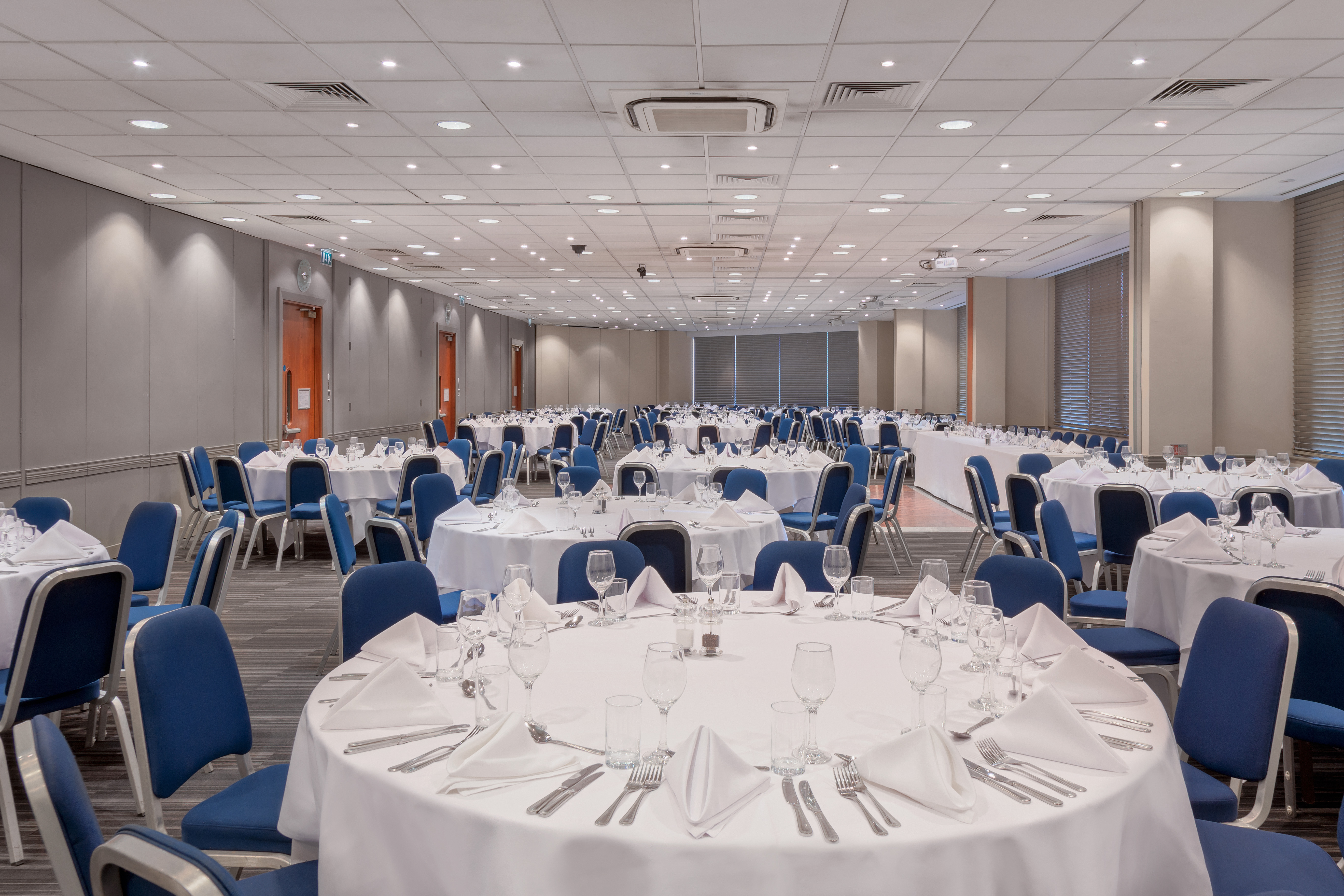 Banquet hall at Holiday Inn Kensington, set for events with elegant decor and blue chairs.