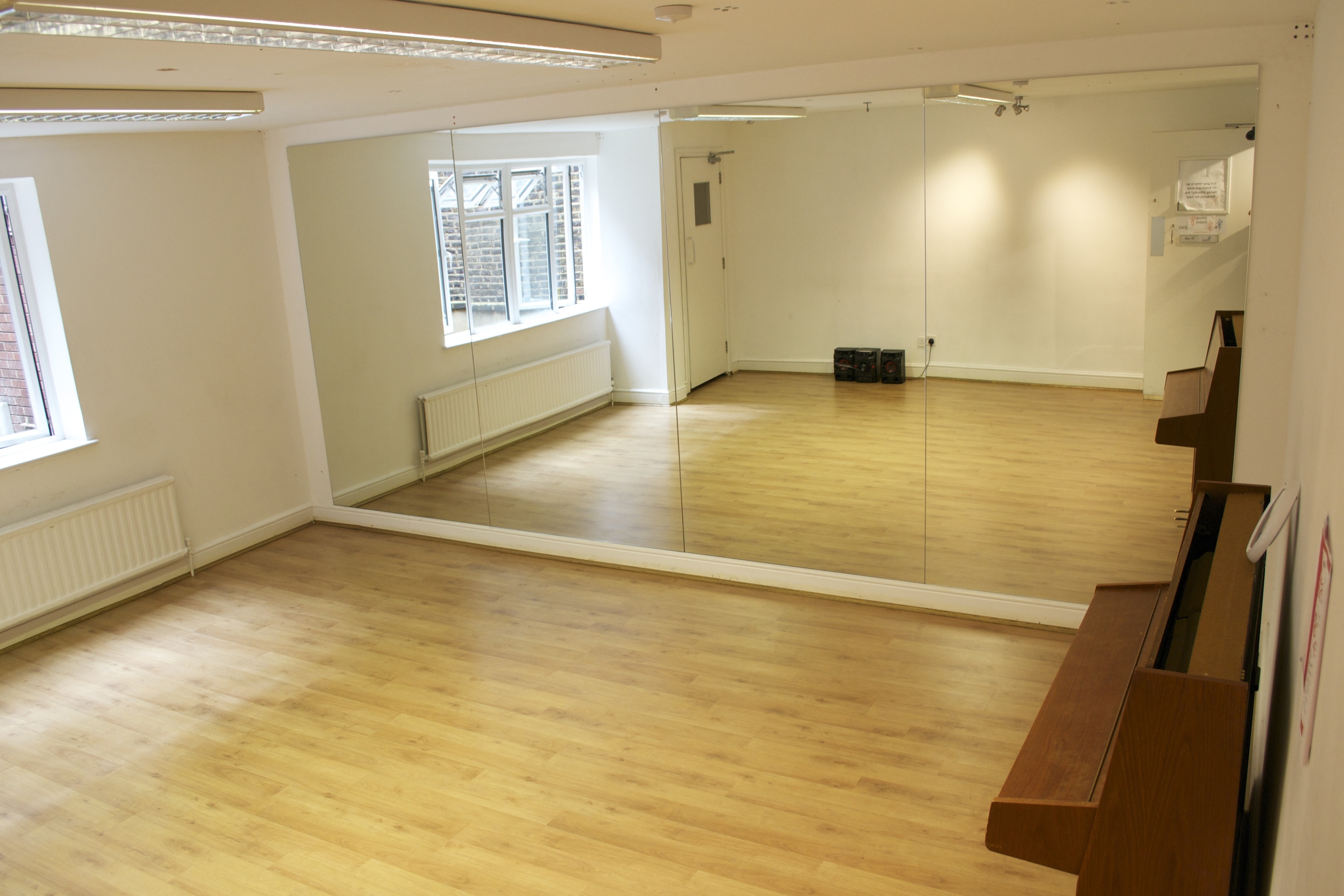 Versatile event space with wooden flooring and mirrors, perfect for workshops and fitness classes.