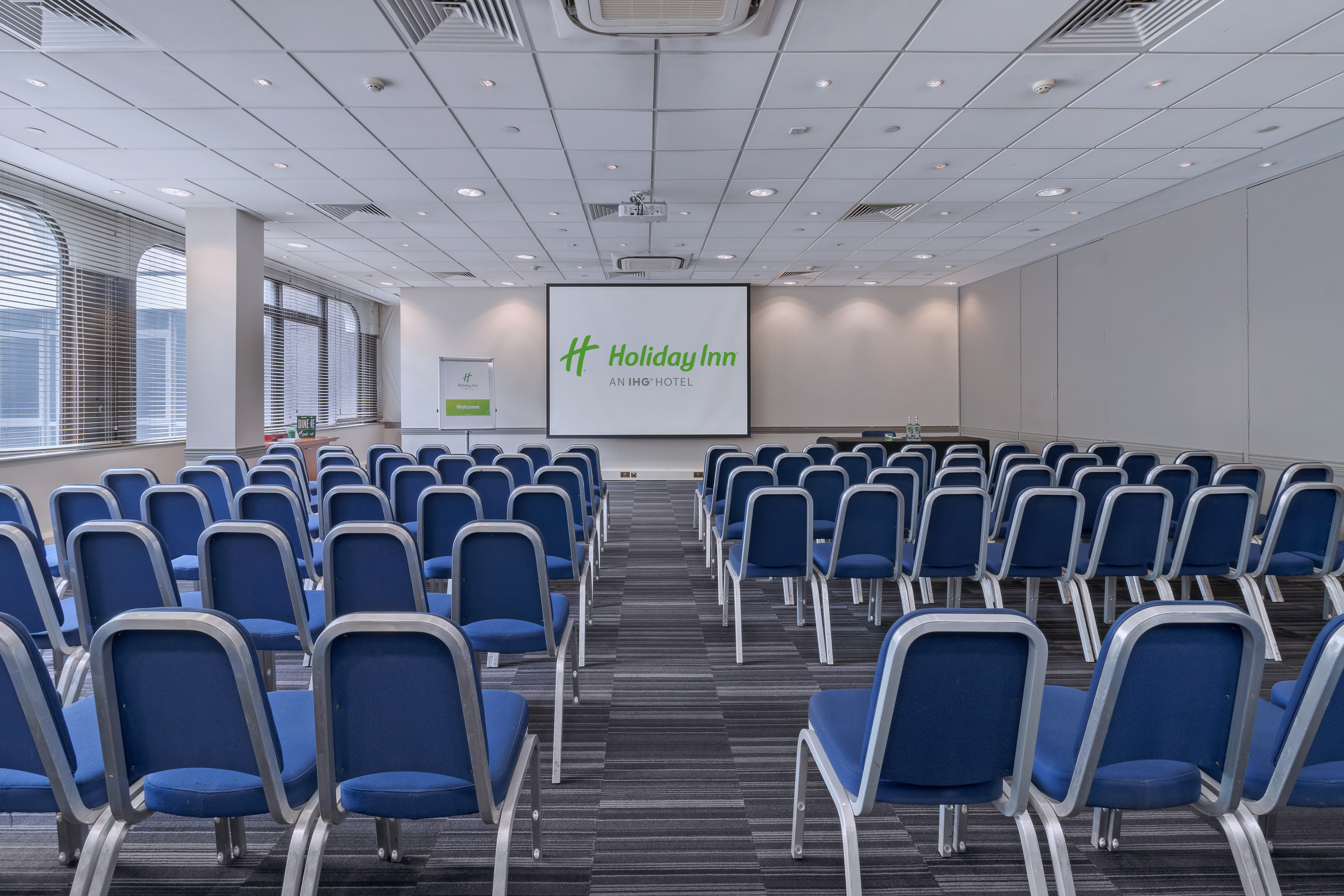 Conference room with blue chairs at Holiday Inn London Kensington Forum for events.