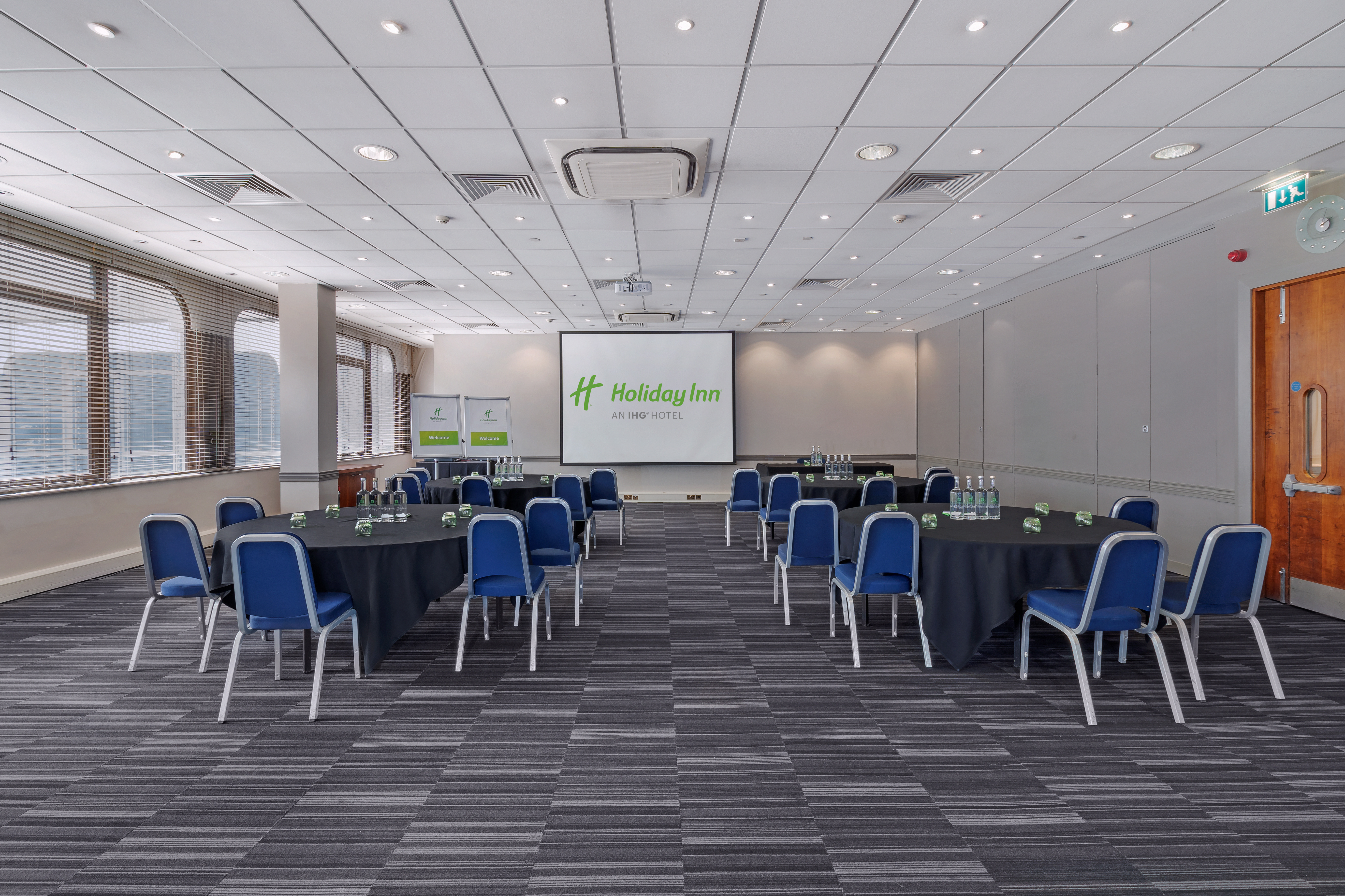 Dylan in a bright Holiday Inn meeting room with round tables for events and workshops.