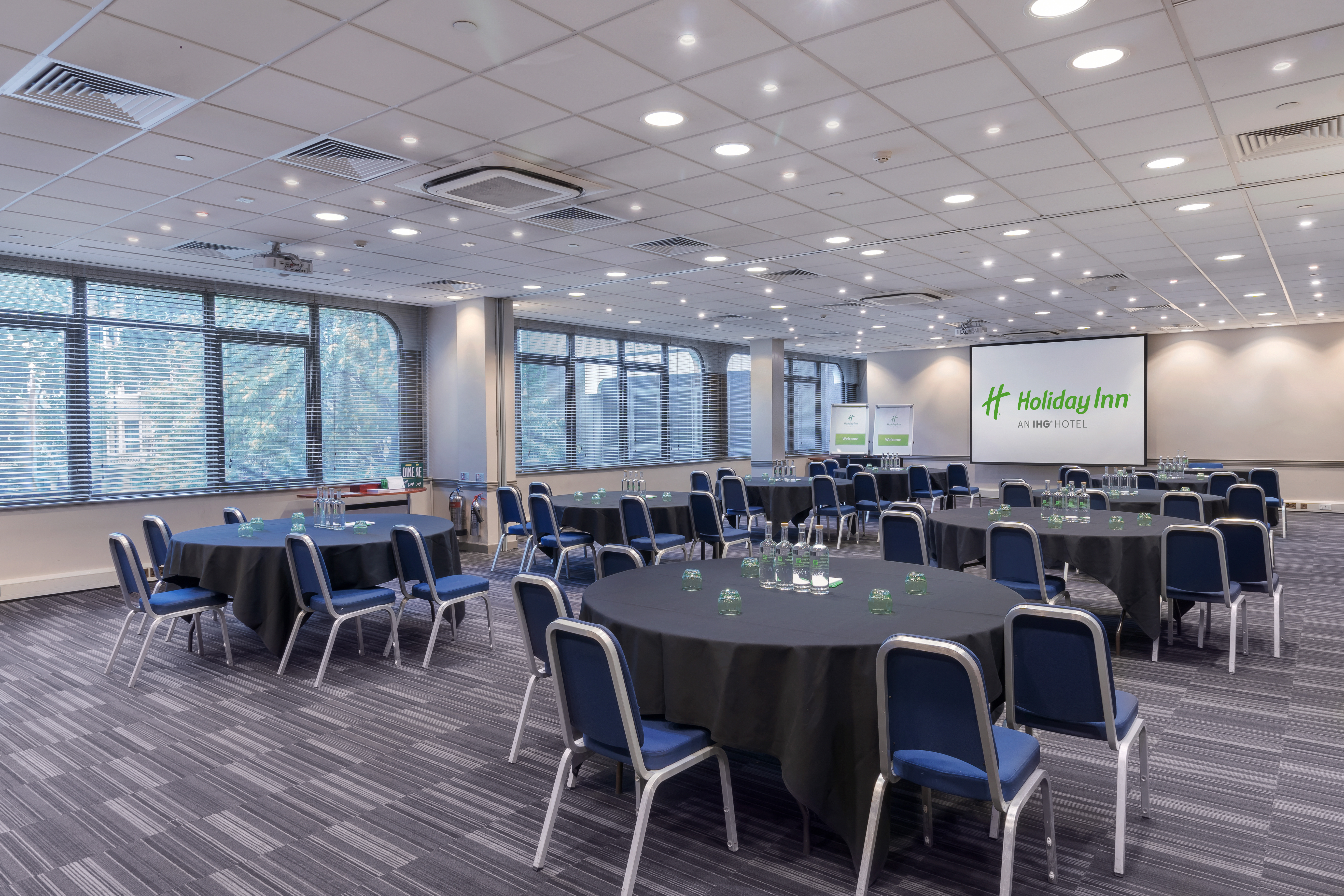 Meeting room at Holiday Inn London with round tables, ideal for events and presentations.