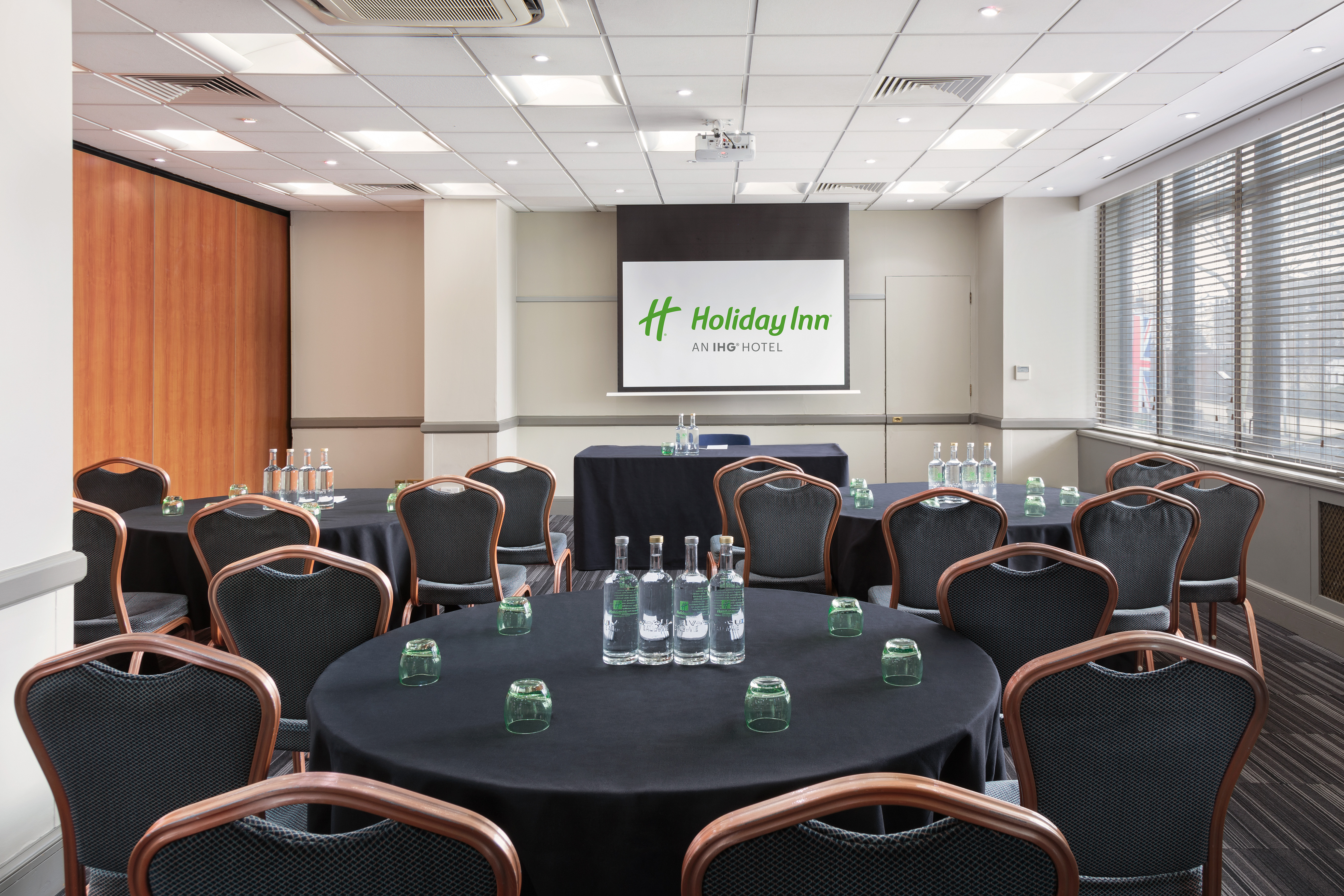 Meeting room at Holiday Inn London with round tables, ideal for corporate events.