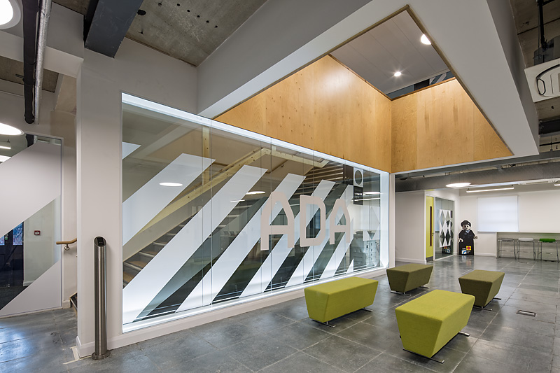 Modern boardroom with glass walls and green seating for meetings at Ada National College.