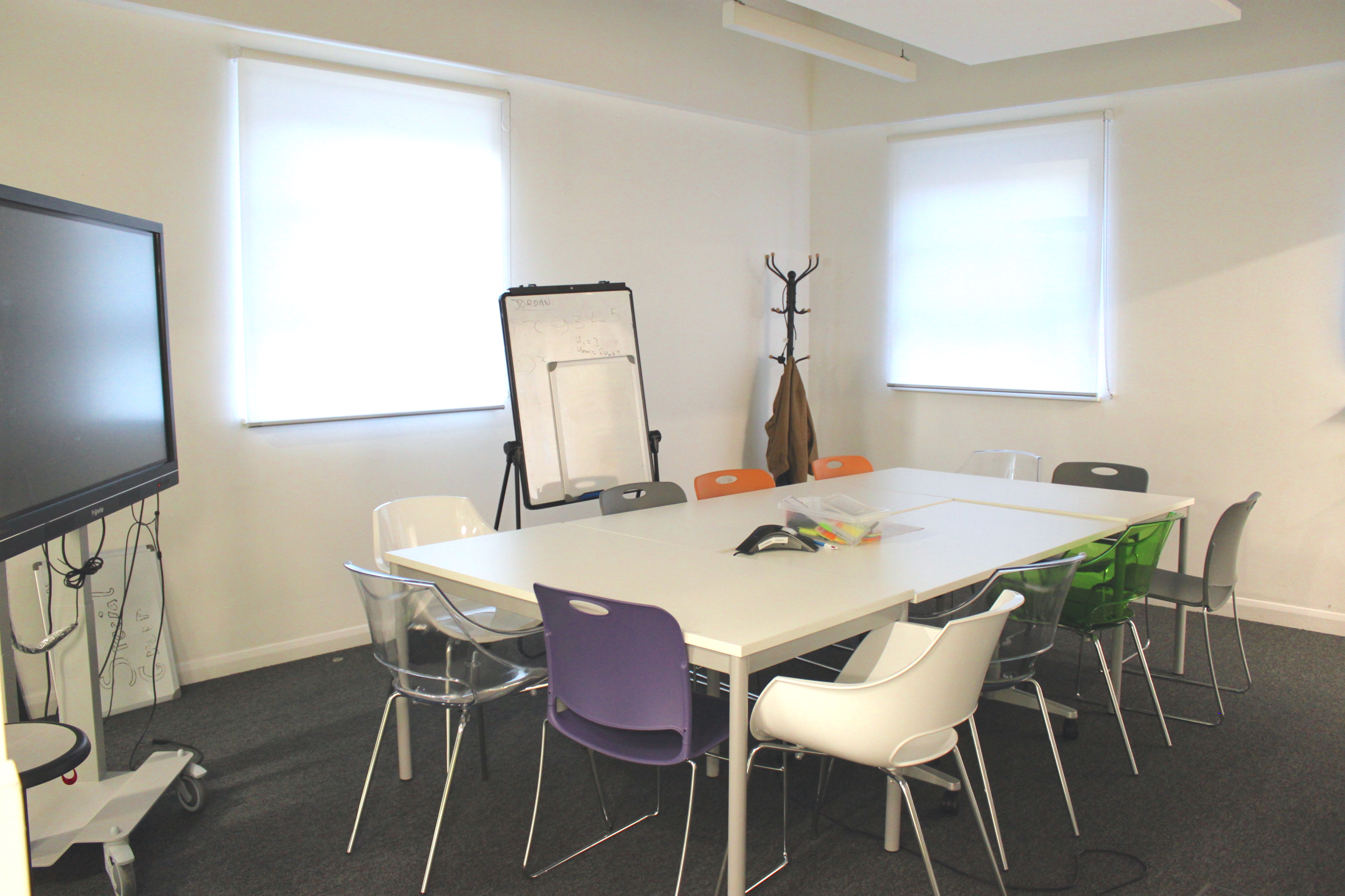 Modern boardroom with colorful chairs, ideal for workshops and team meetings.