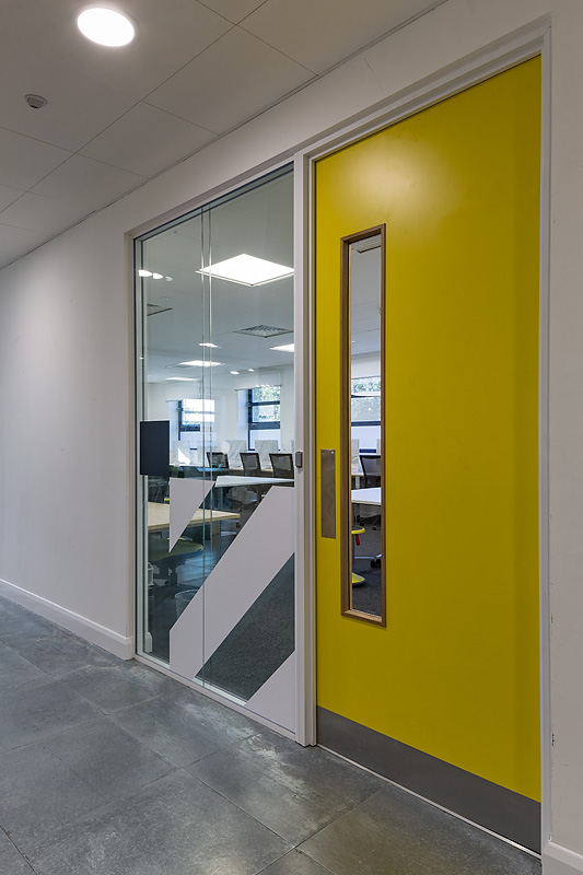 Modern meeting room entrance with vibrant yellow door at Ada National College for workshops.