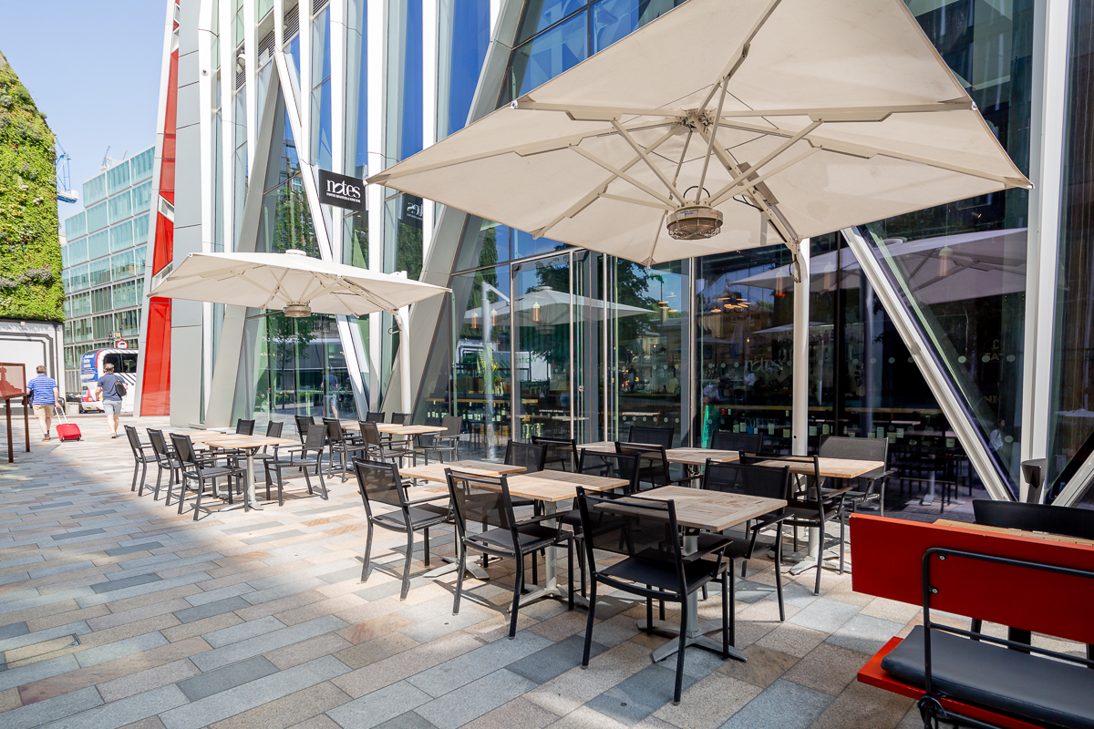 Outdoor event space at Notes Victoria with modern furniture and large umbrellas for shade.