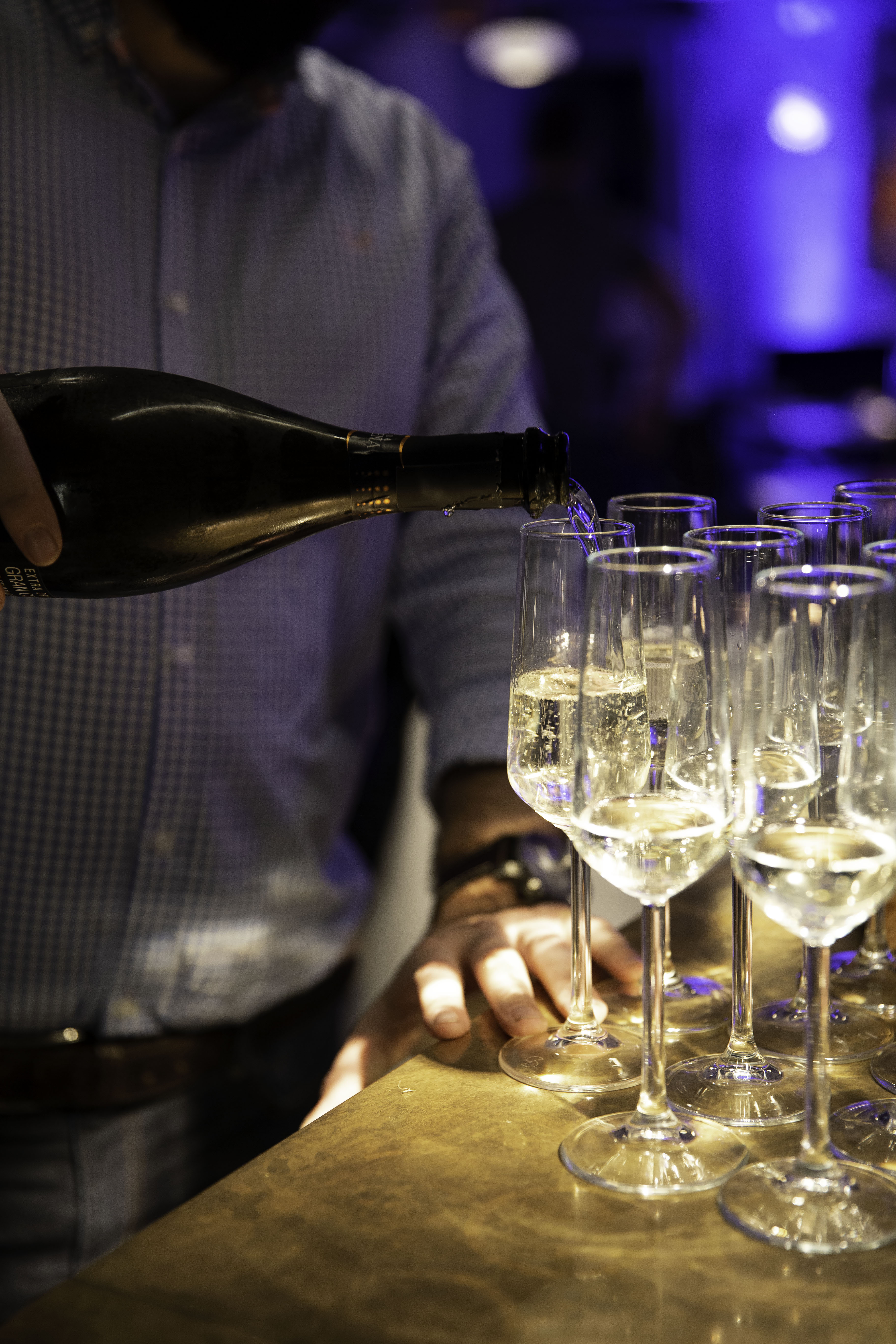 Professional pouring sparkling wine into flutes at Double Boat Hire, Darcie & May event.