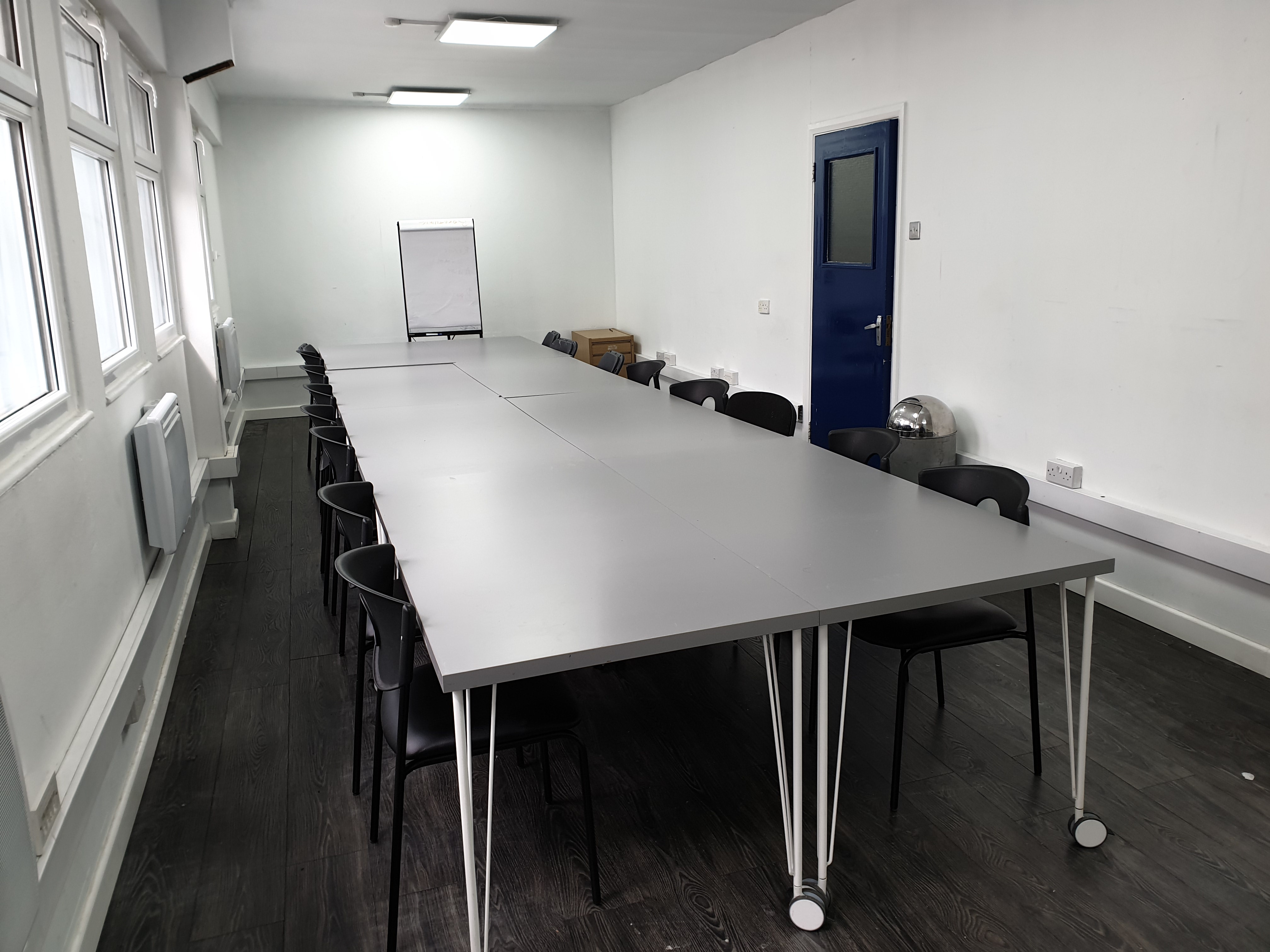 Spacious minimalist meeting room with sleek table, ideal for workshops and team meetings.