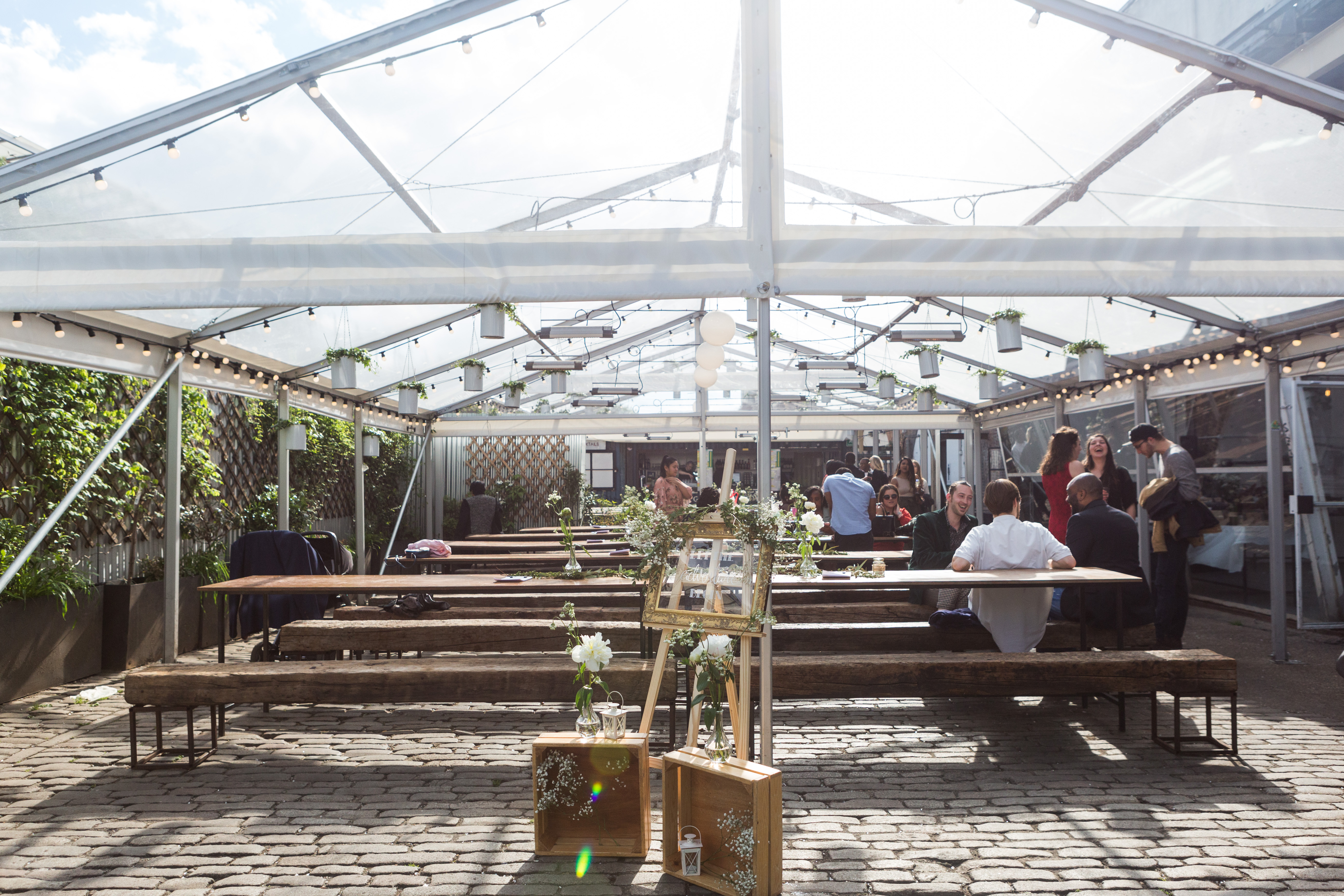 Palm House in Peckham Springs: outdoor event space with wooden tables for weddings and gatherings.
