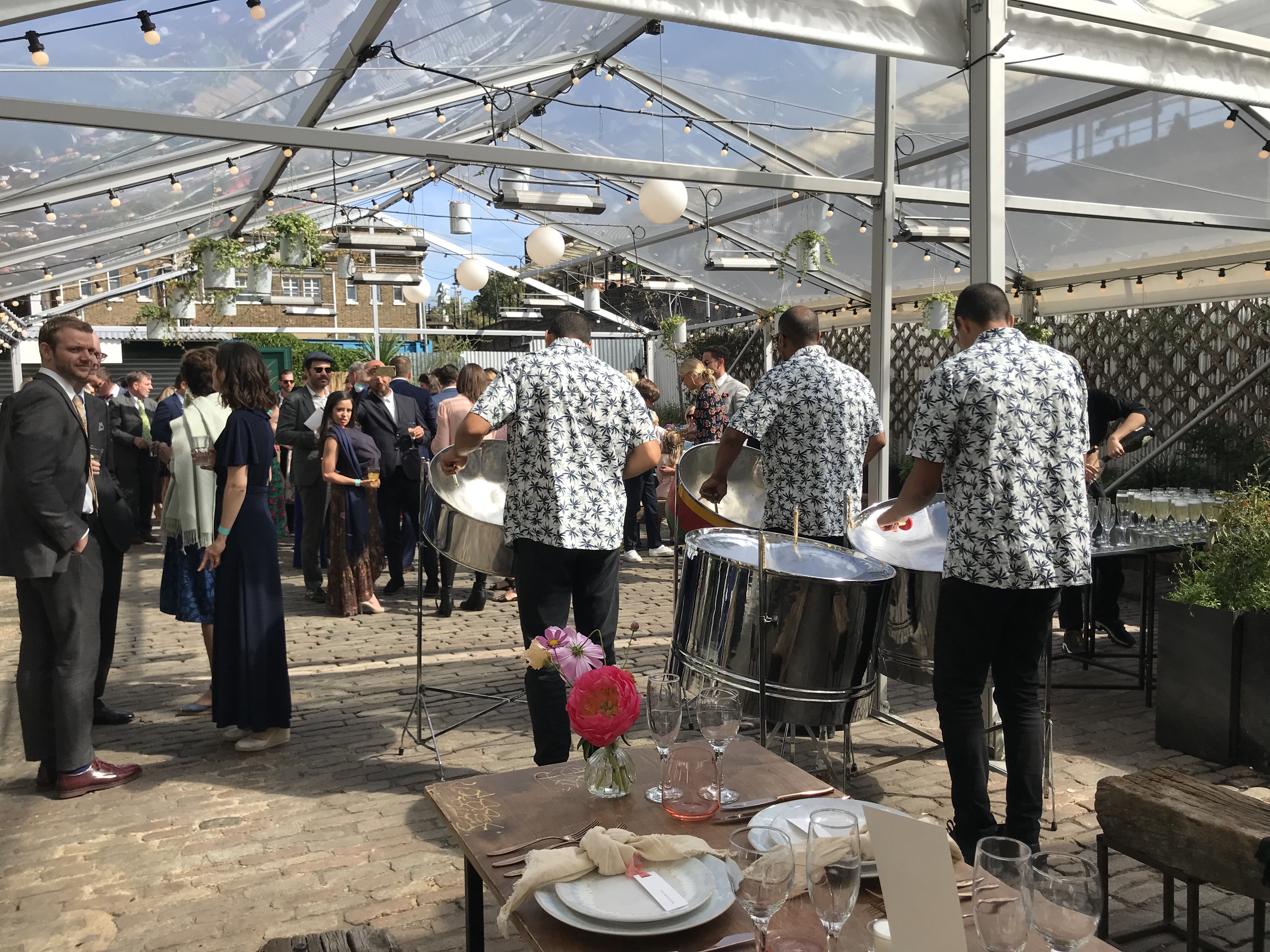 Outdoor event at Peckham Springs under a clear tent with vibrant floral arrangements.