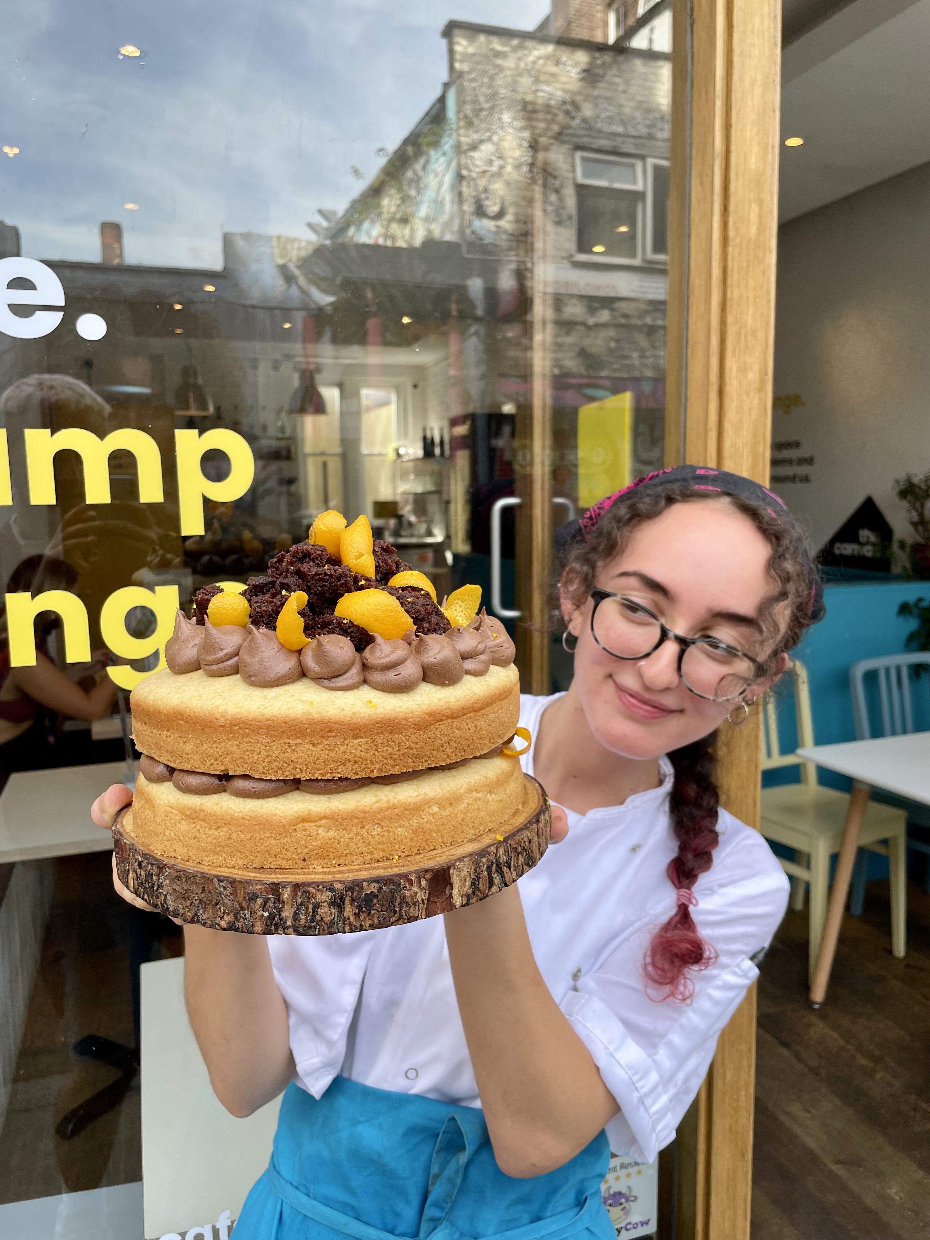 Pastry chef showcasing a decorative cake for events at Cafe in The Canvas.