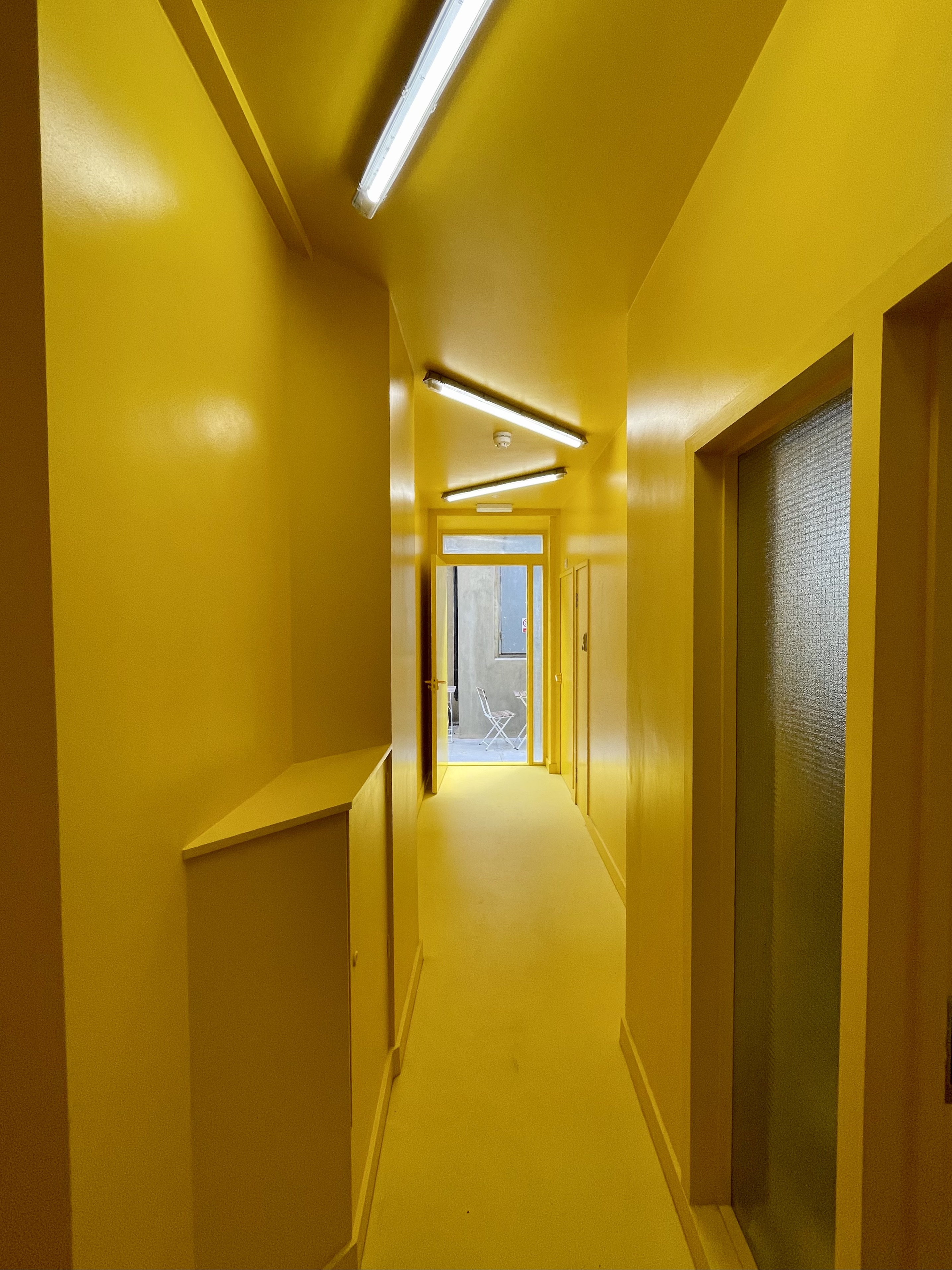 Vibrant yellow corridor in Cafe The Canvas, perfect for creative workshops and events.