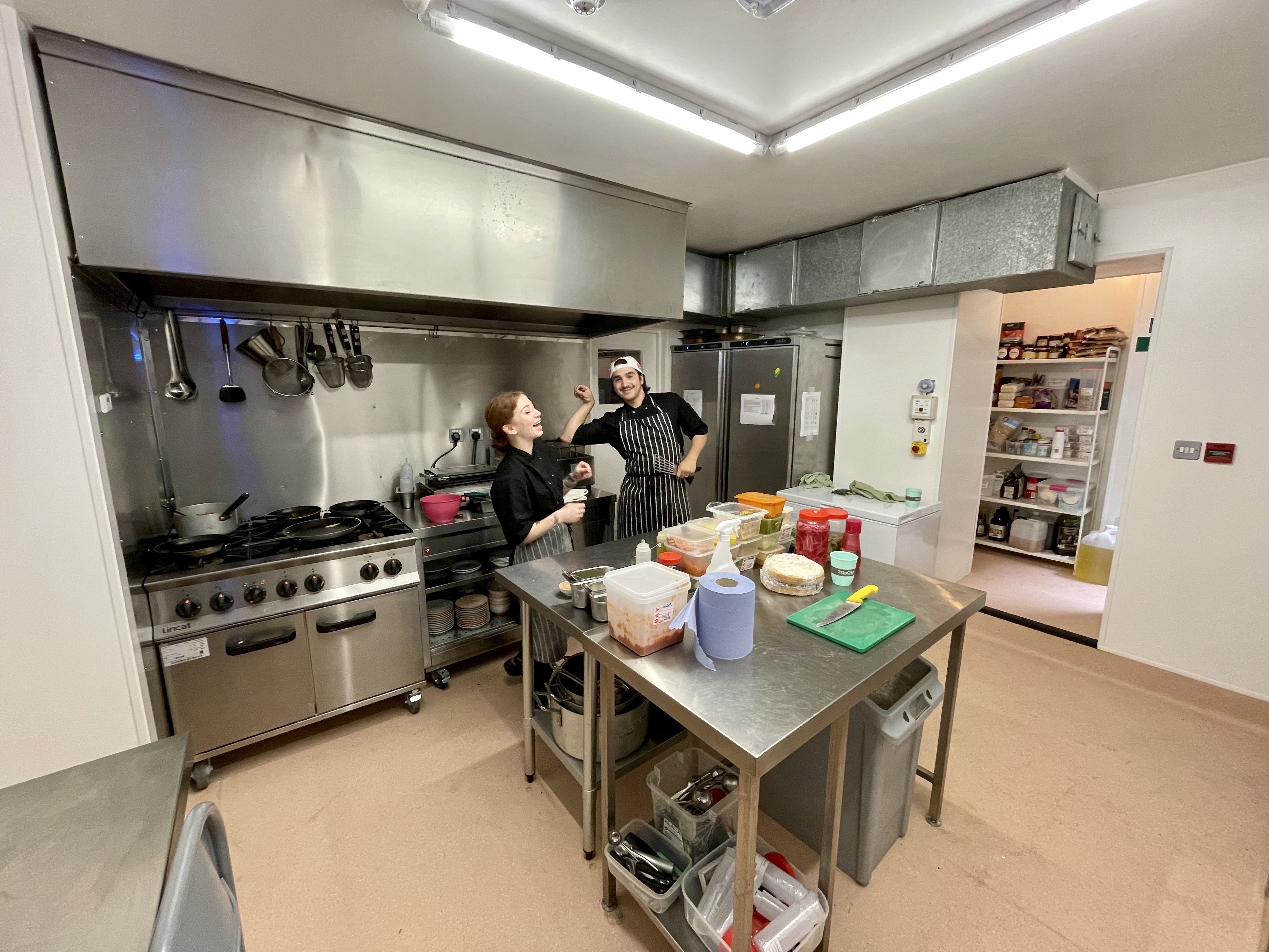 Chefs in professional attire at a well-equipped catering kitchen in The Canvas.
