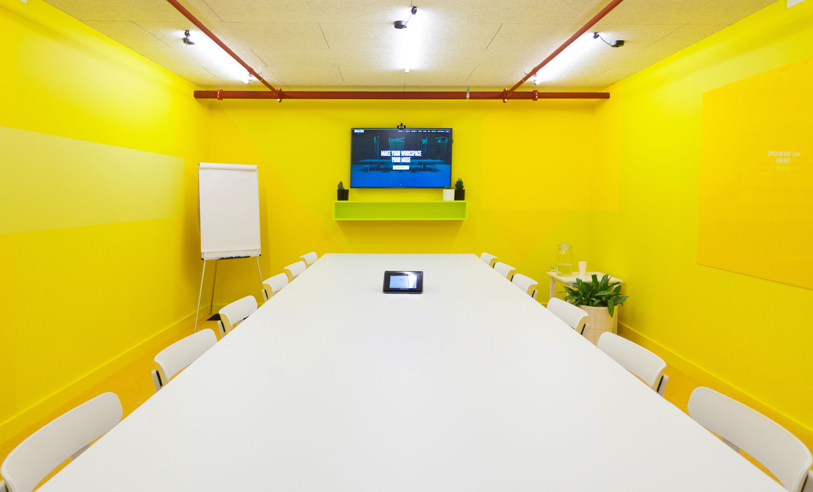 Vibrant yellow meeting room at Huckletree West for creative team meetings.
