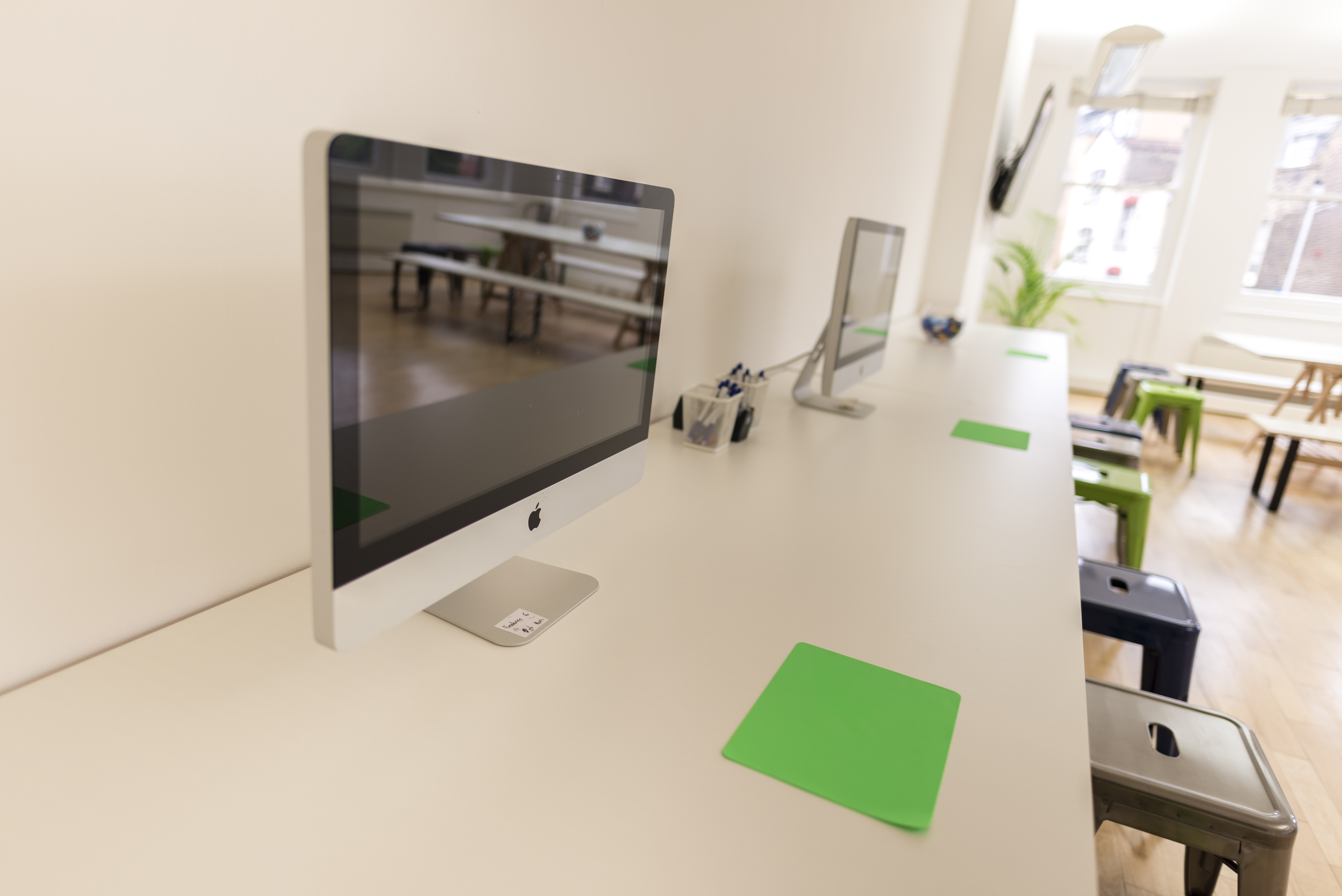 Modern collaborative workspace with iMacs at Earls Court Community Hub for events.
