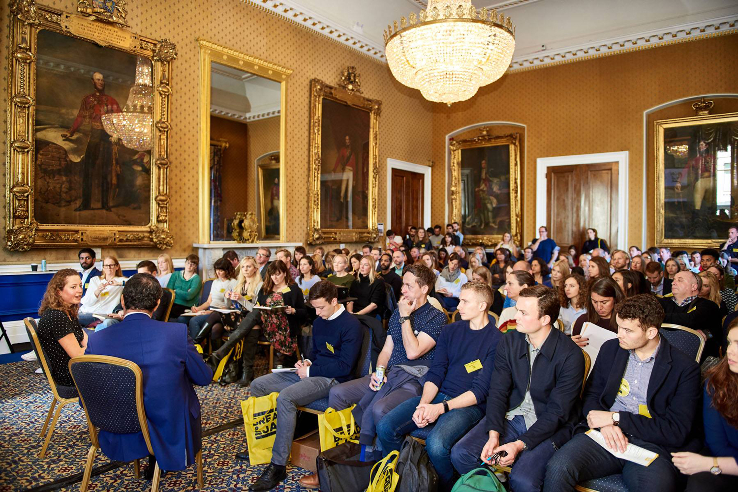 Elegant conference at Waterloo, 116 Pall Mall, featuring diverse audience and upscale decor.