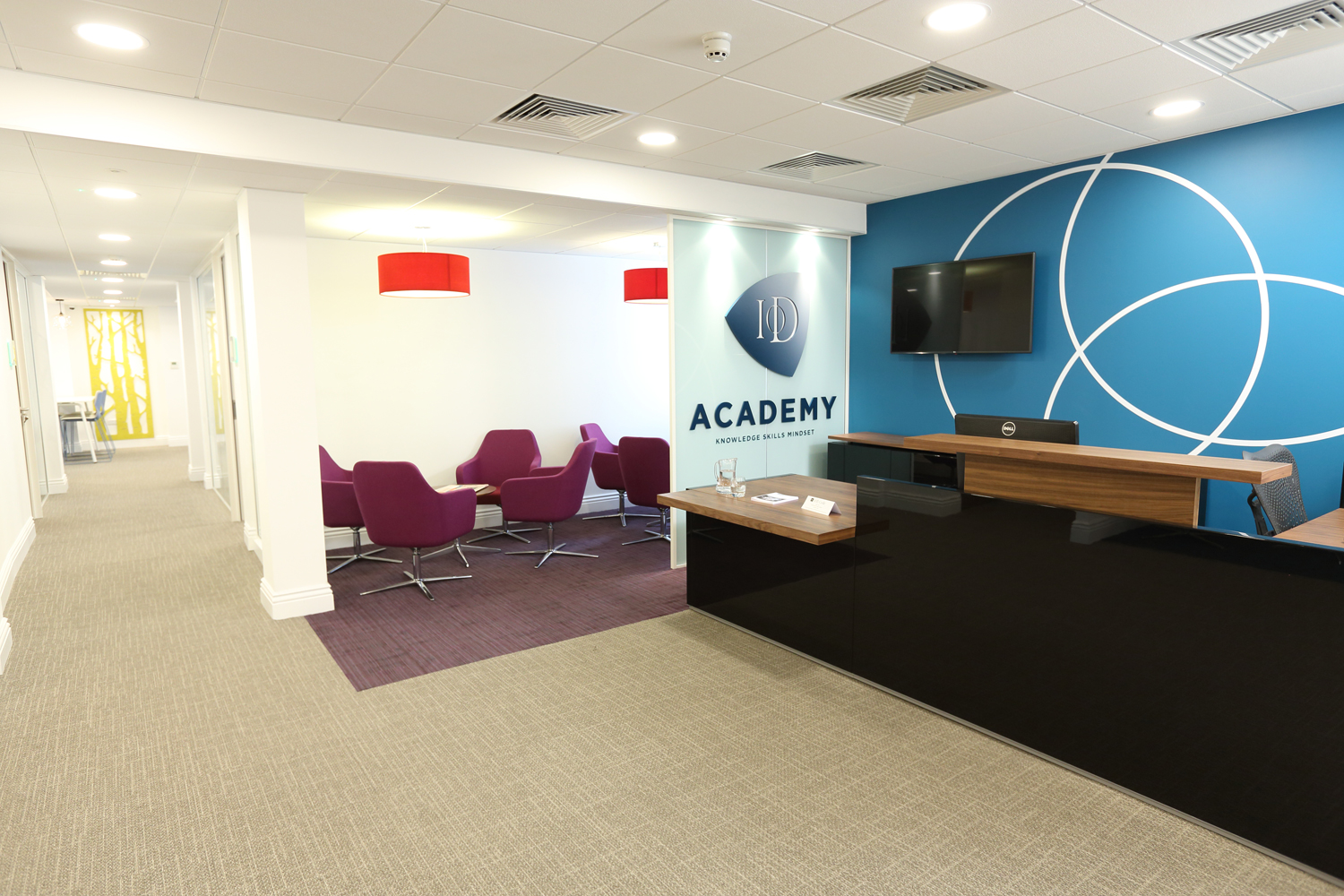 Modern reception area at IoD Academy, featuring sleek desk and vibrant blue wall for events.