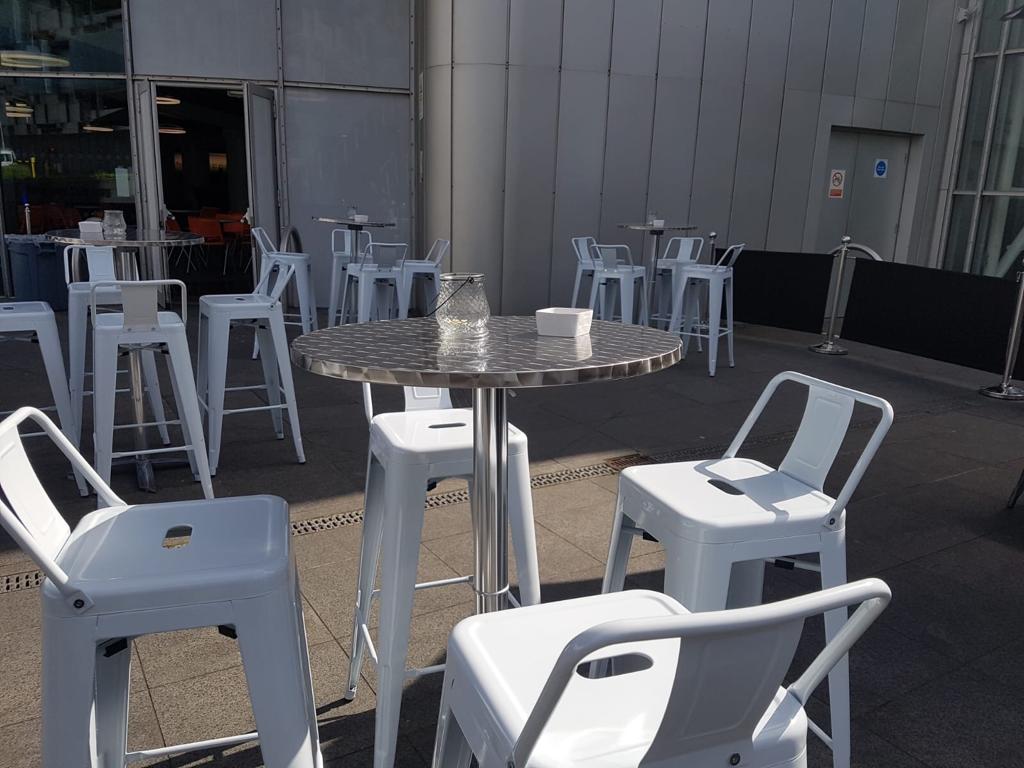 Modern outdoor event space at INGRESS, featuring sleek high-top tables for networking.