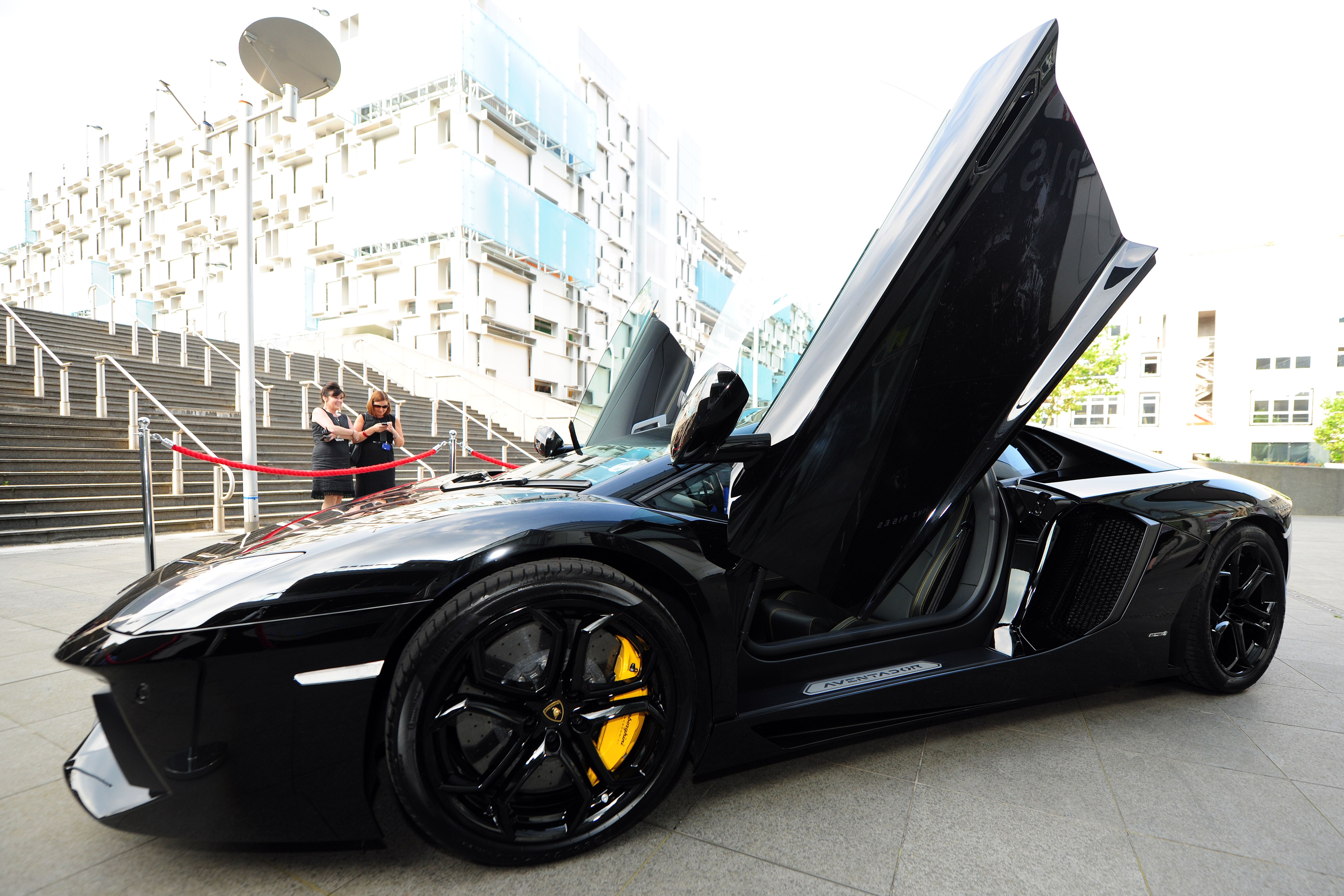 Sleek black sports car with open doors at Millennium Point for luxury events and photo ops.