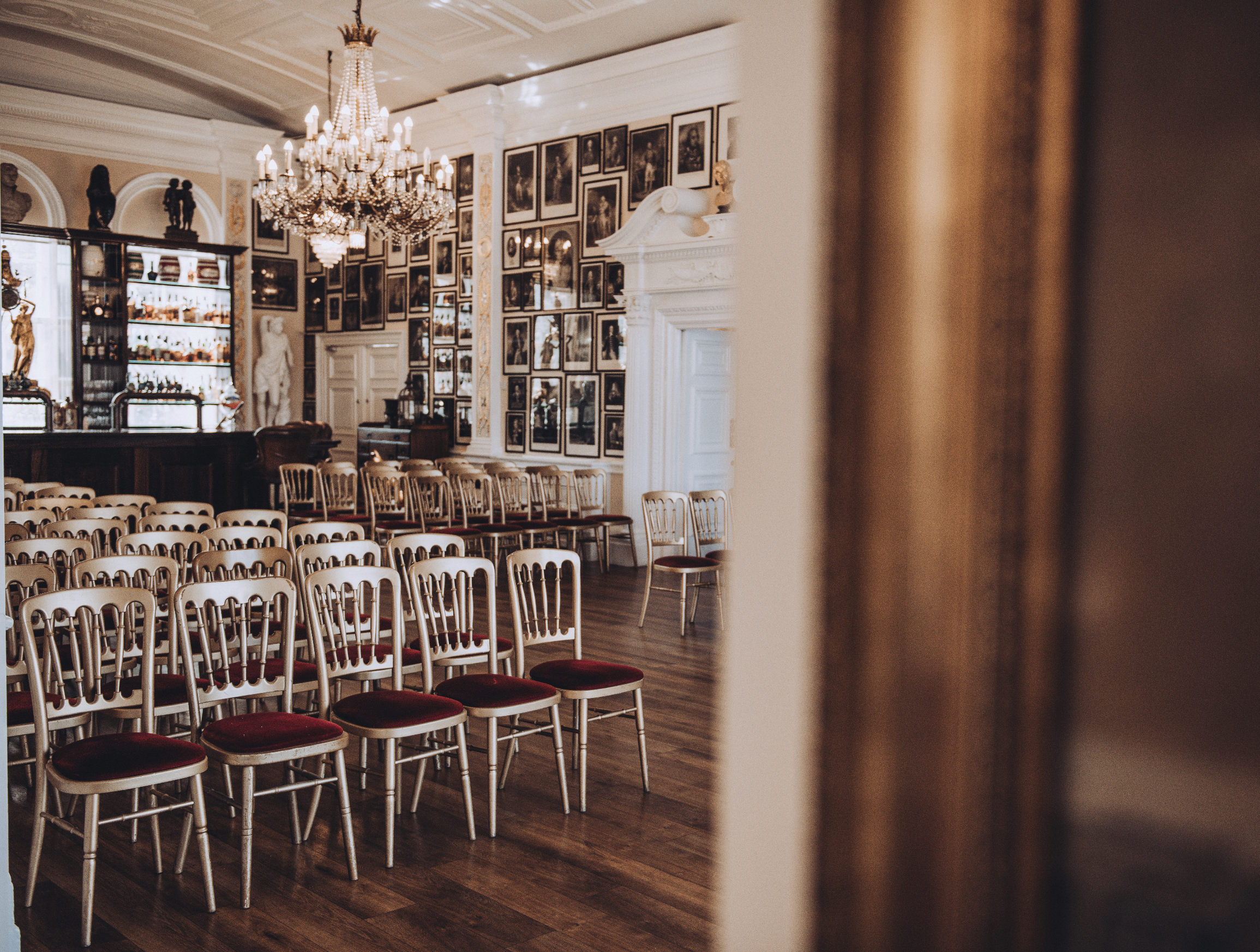 Elegant event space in Nelson Room, Trafalgar Tavern with white chairs and red cushions.