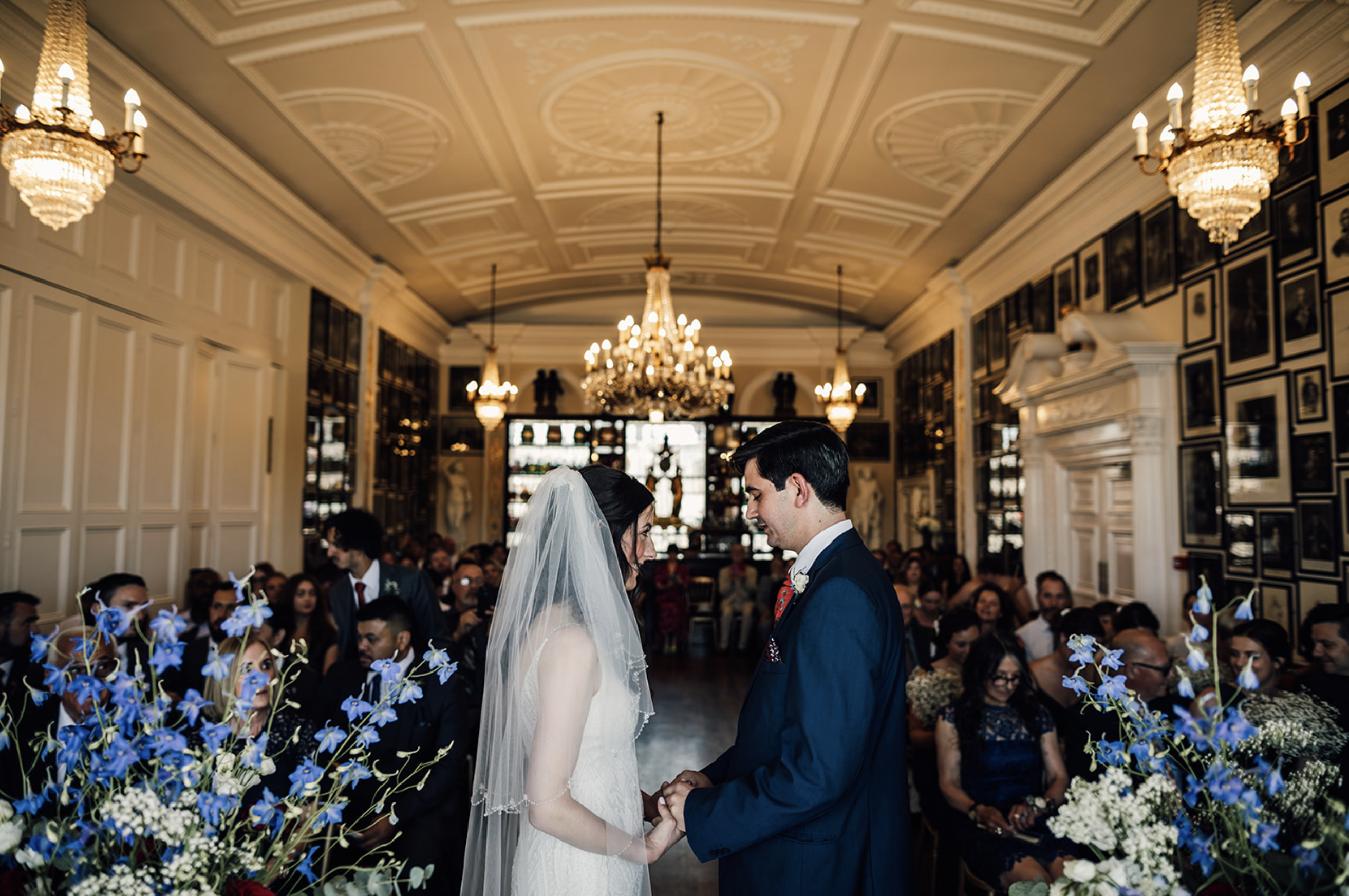 Elegant wedding ceremony in Nelson Room, Trafalgar Tavern with ornate chandeliers.