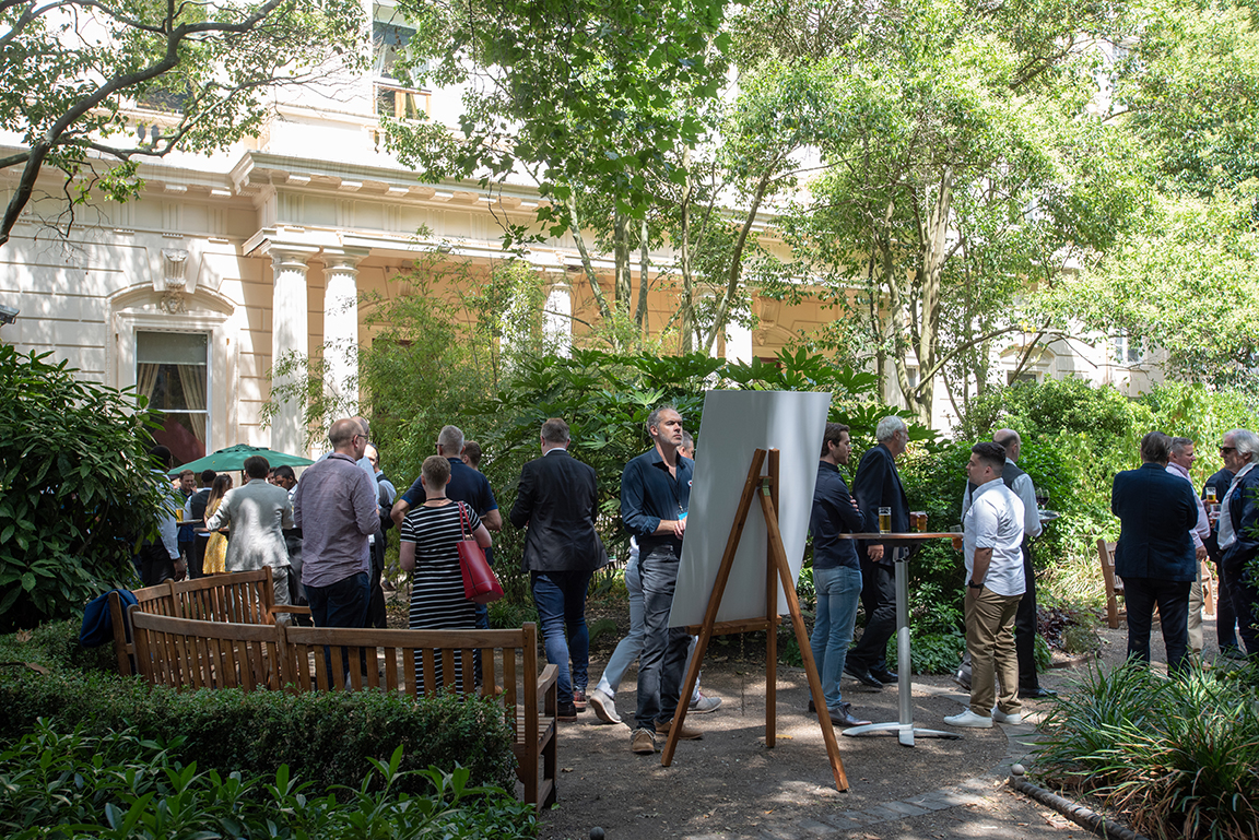 Outdoor networking event in Carlton Room, 116 Pall Mall, with lush greenery and seating.