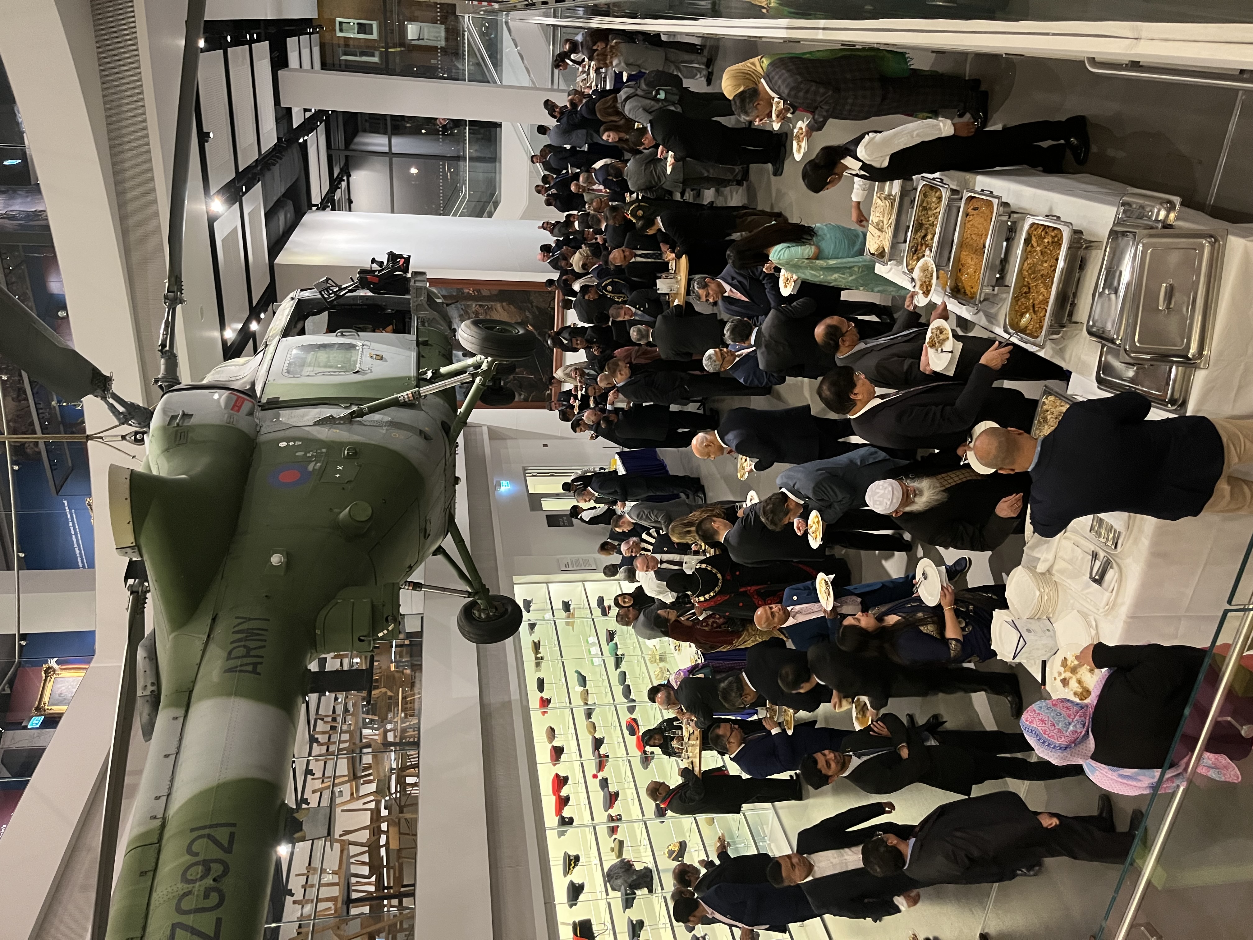 Networking event in National Army Museum Atrium with buffet and diverse attendees.