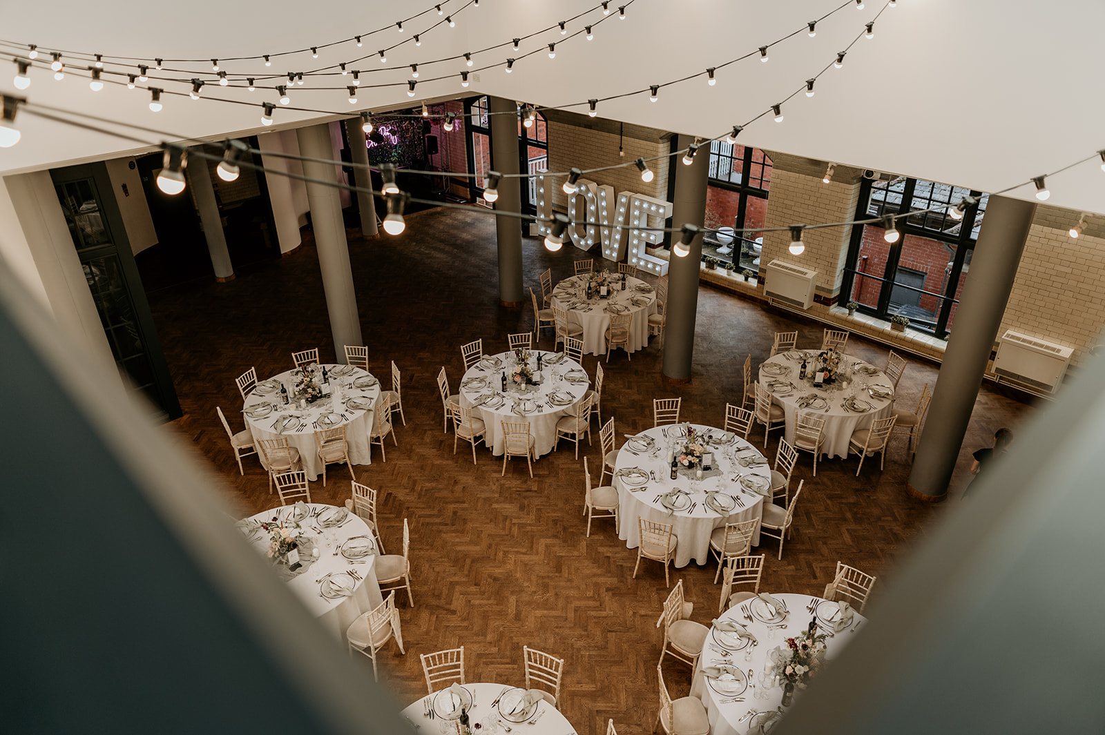 Elegant event space in The Engine Hall, perfect for weddings with round tables and string lights.