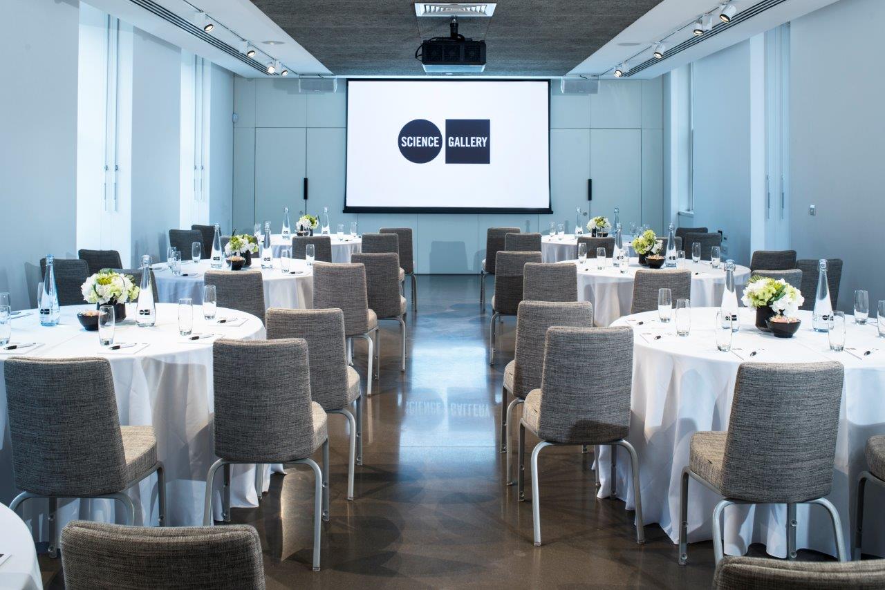 Modern event space with round tables and floral centerpieces for conferences in London.