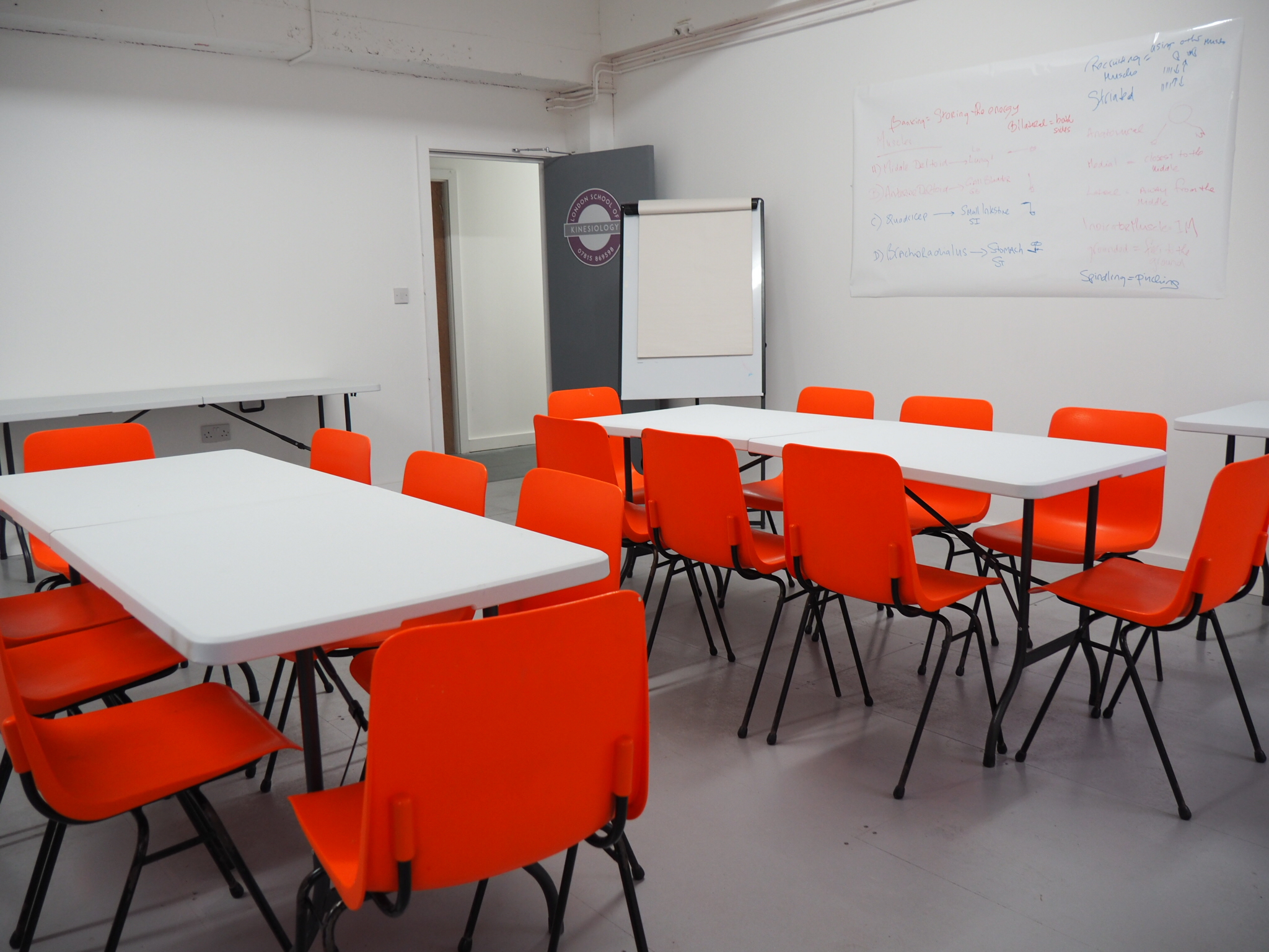 Versatile Wick Lane Studio meeting space with vibrant orange chairs for workshops.
