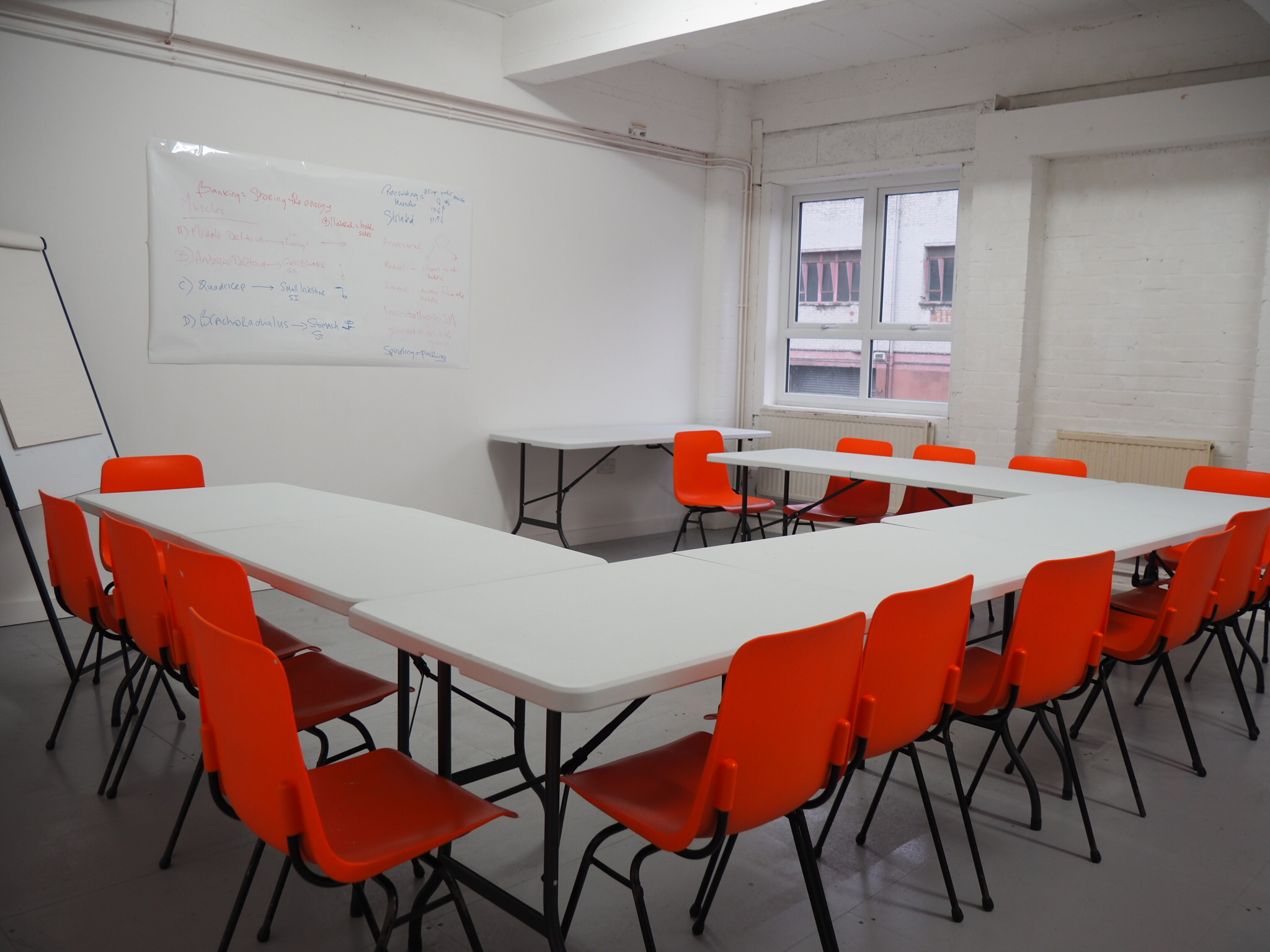 Versatile Wick Lane Studio meeting space with vibrant orange chairs and V-shape setup.