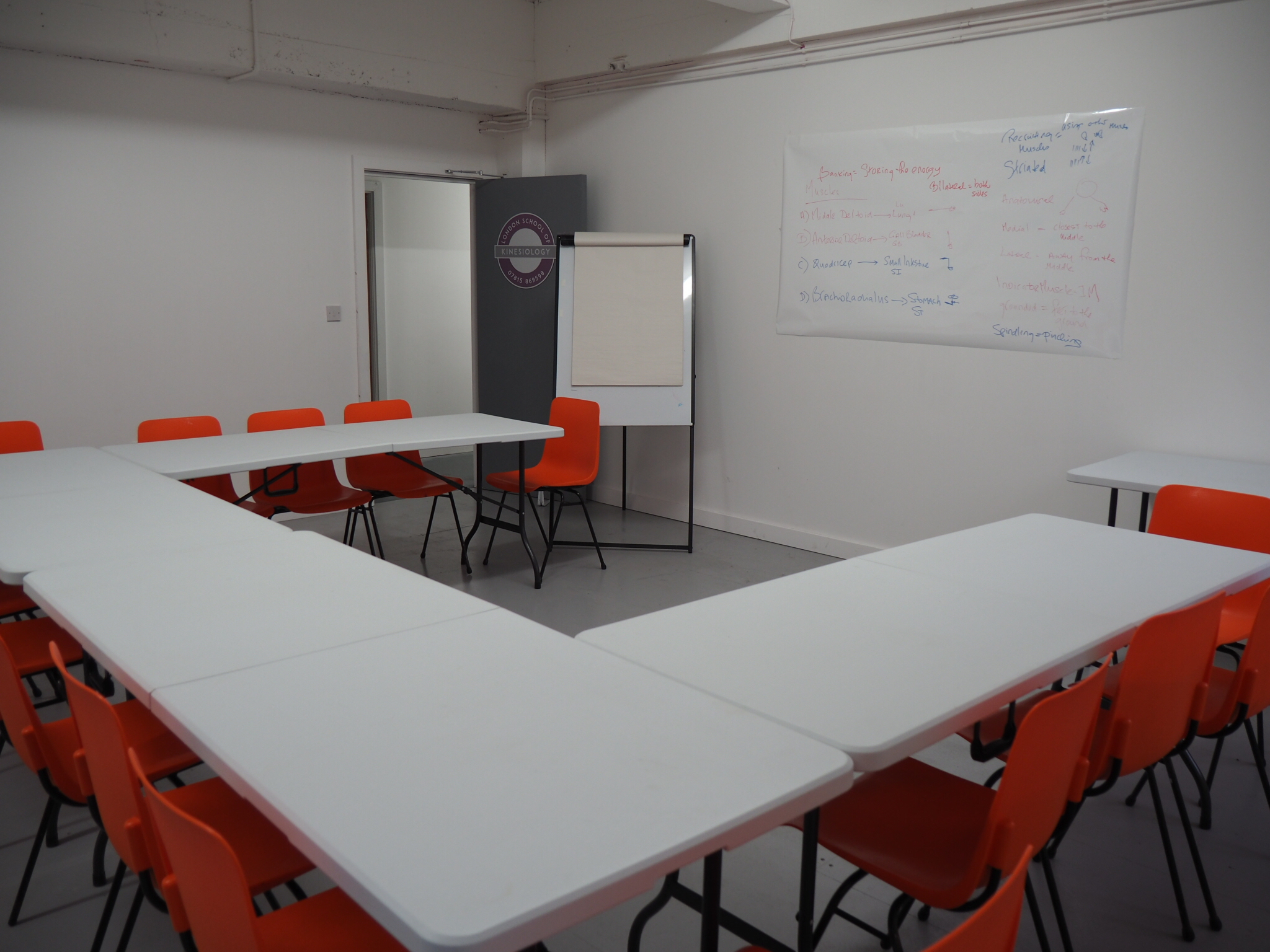 Versatile U-shaped meeting room with orange chairs, perfect for workshops and team meetings.