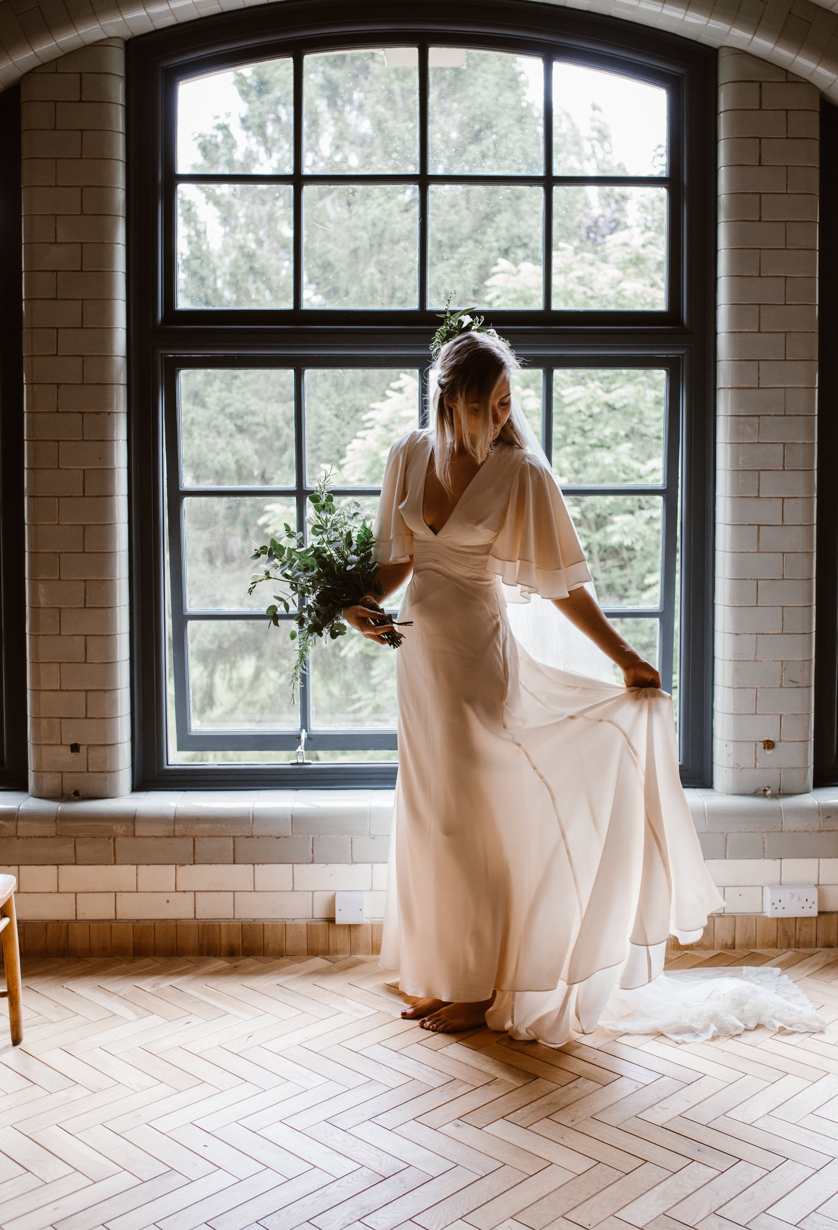 Bride in flowing gown by window in The Ollerton Room, ideal for weddings and receptions.