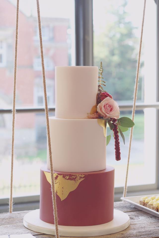 Elegant two-tier wedding cake with fresh flowers on a swing at upscale event.