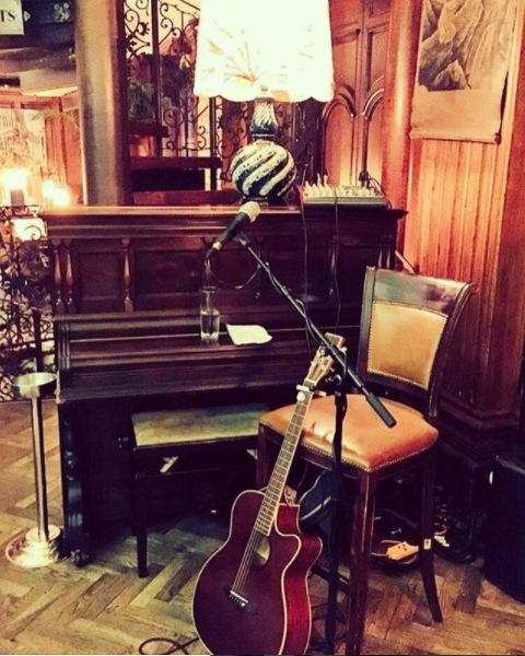 Cozy live music setup with microphone, guitar, and vintage piano at The Mezzanine.