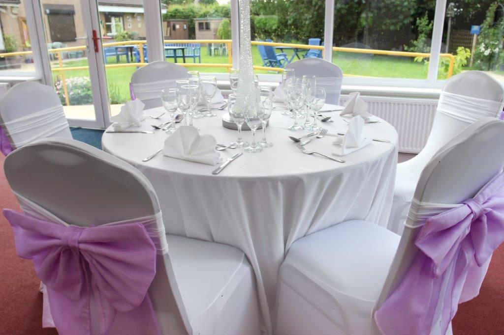 Iris Conservatory table setting with lavender bows, perfect for weddings and formal events.