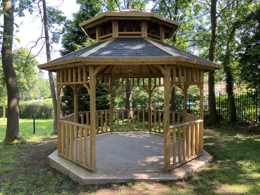 Wooden gazebo in lush setting, perfect for weddings and outdoor events.