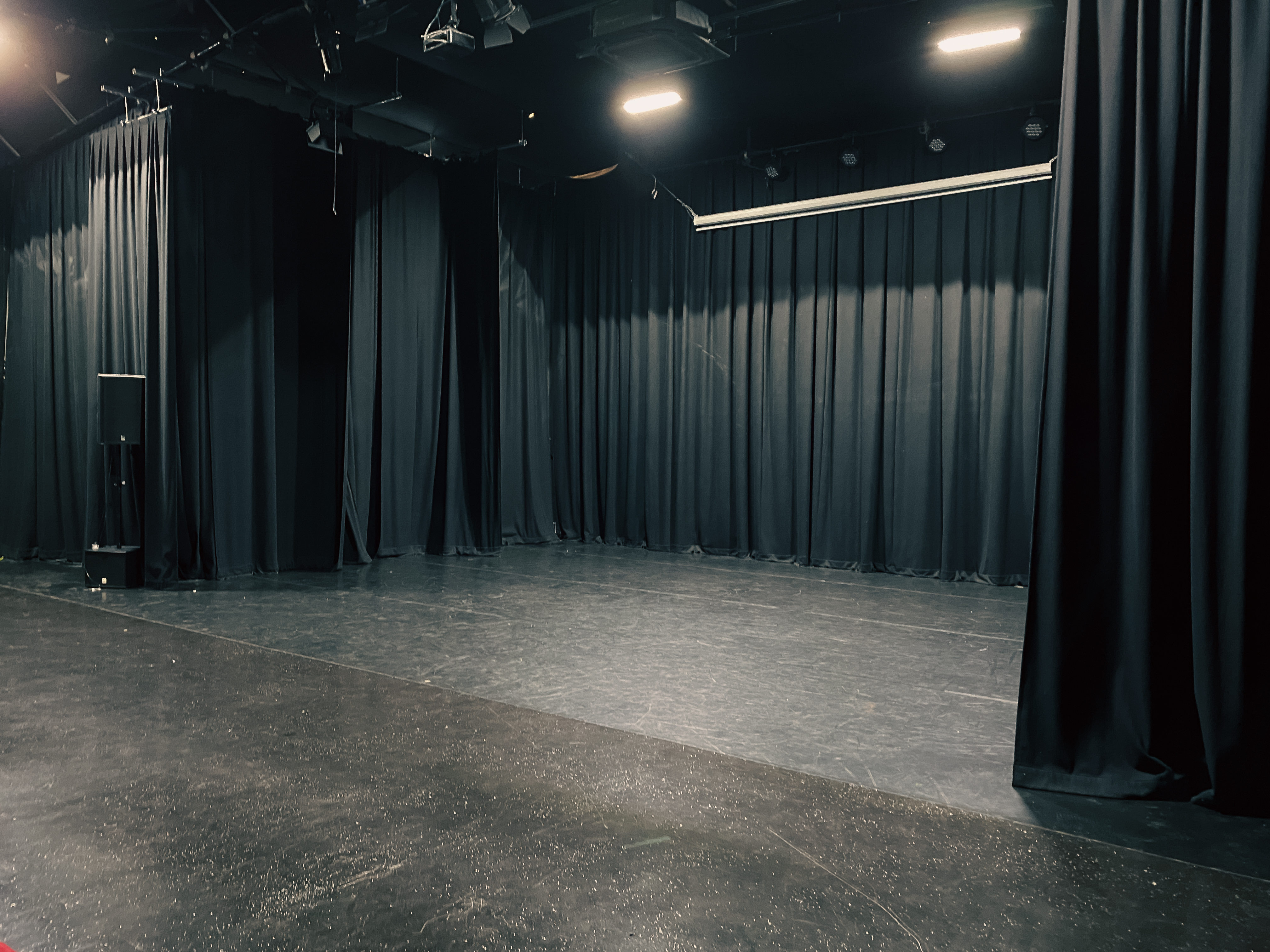 Versatile event space with black drapery for corporate meetings and performances.