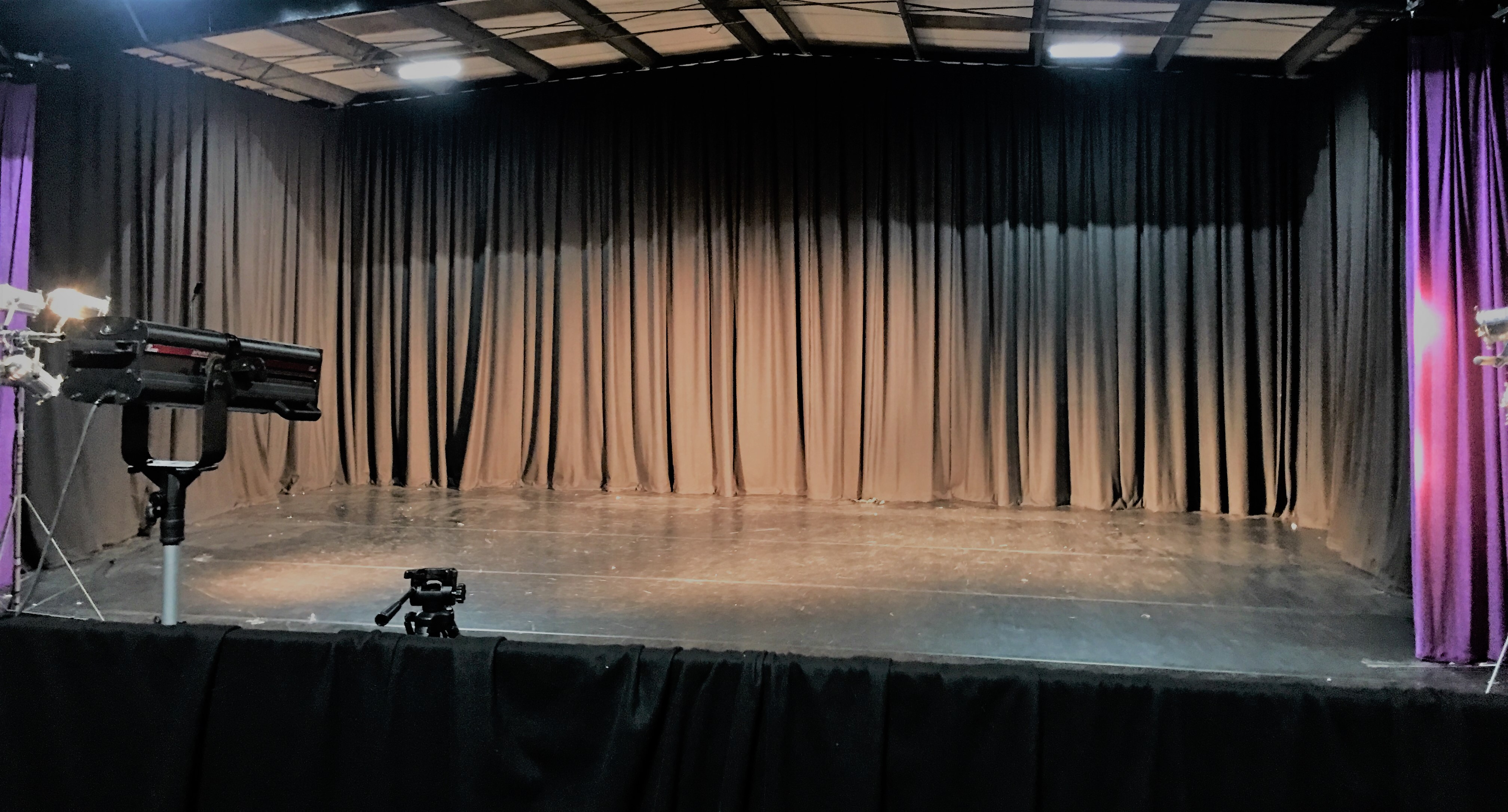Blank stage with black curtain in The Empty Space for events, presentations, and performances.
