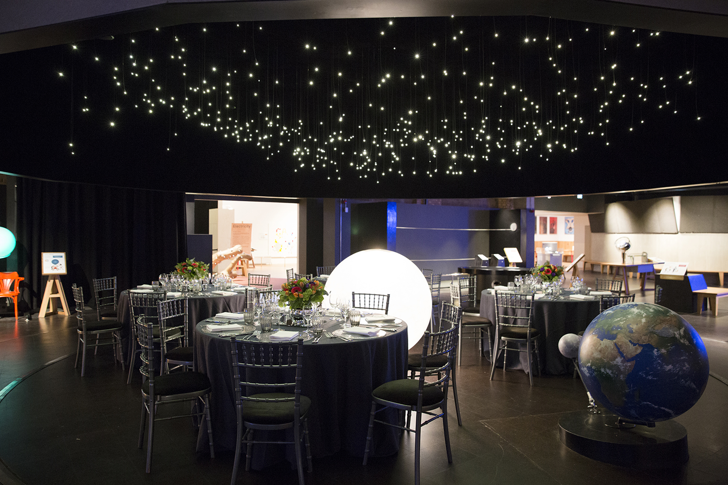 Elegant event space at Wonderlab, featuring round tables and a starry ceiling for galas.