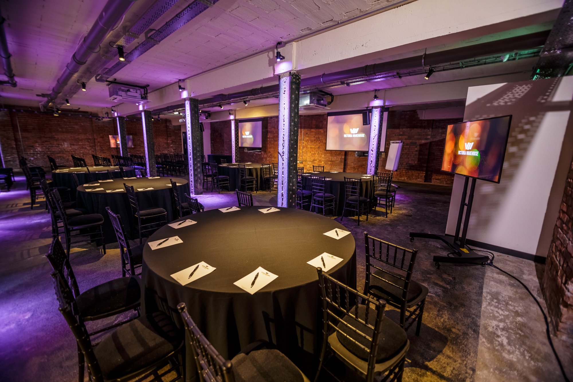 Versatile meeting space at The Cellars, Victoria Warehouse with round tables and ambient lighting.