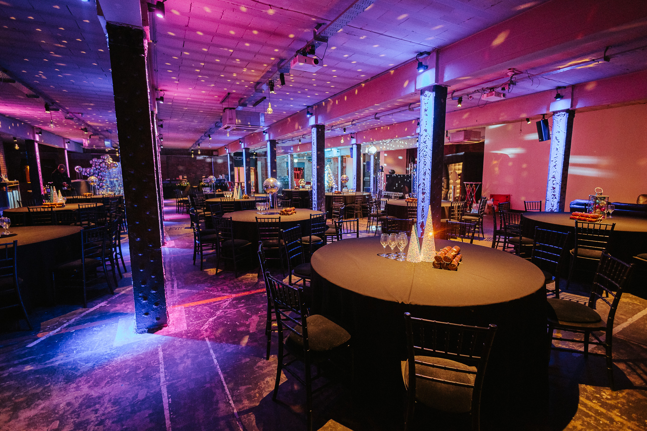 Versatile event space at The Cellars, Victoria Warehouse with ambient lighting and round tables.