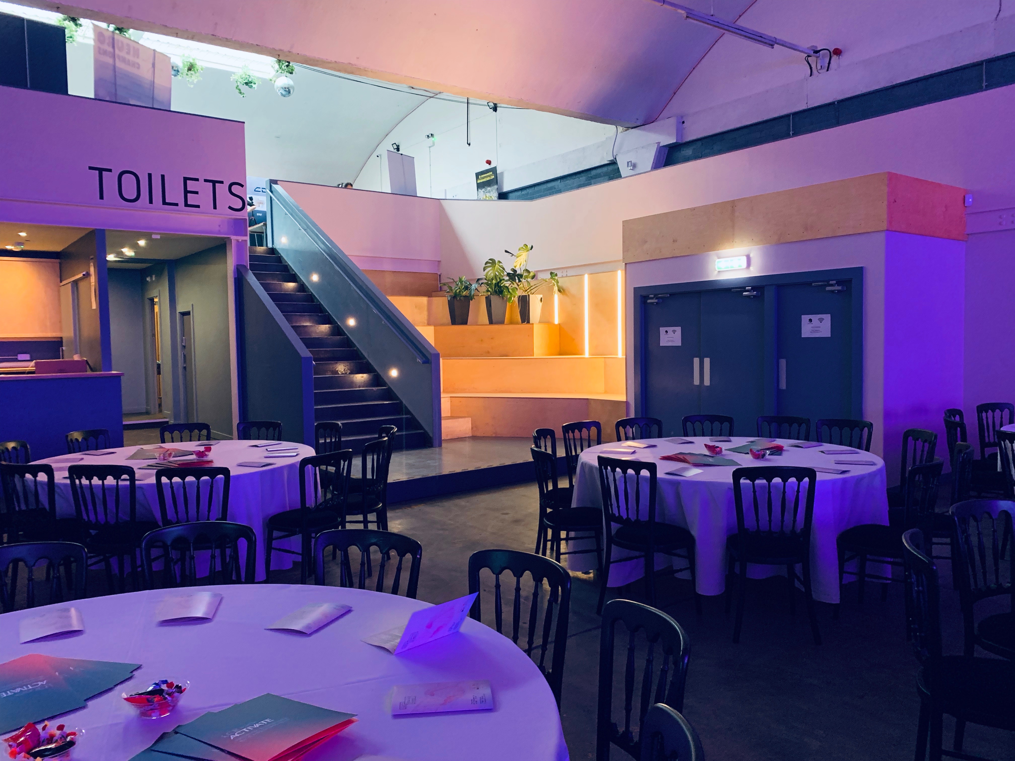 Versatile event hall in Hinterlands with dining tables and elevated stage for gatherings.