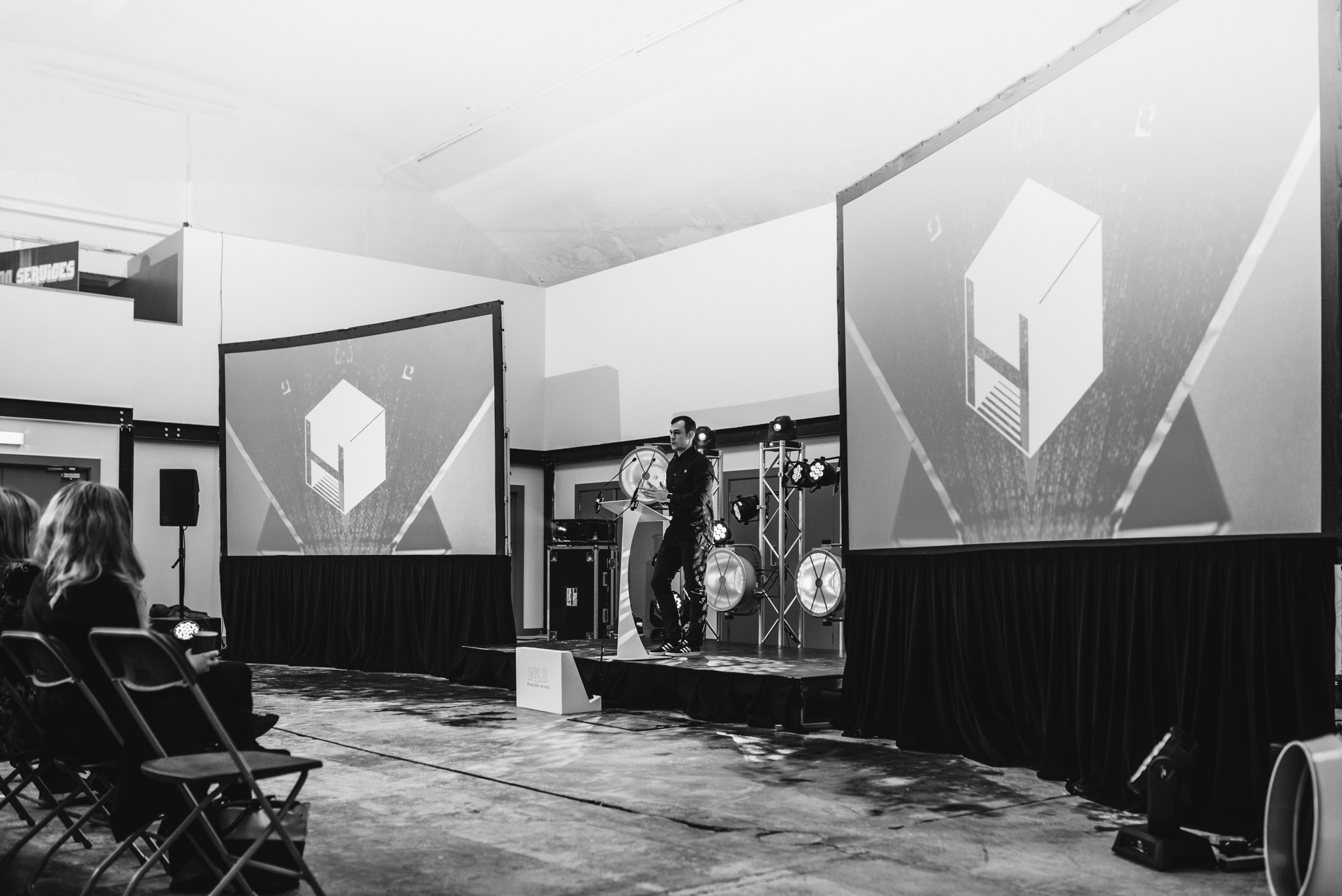 Event Hall in Hinterlands set for a presentation with engaging speaker and dual projection screens.